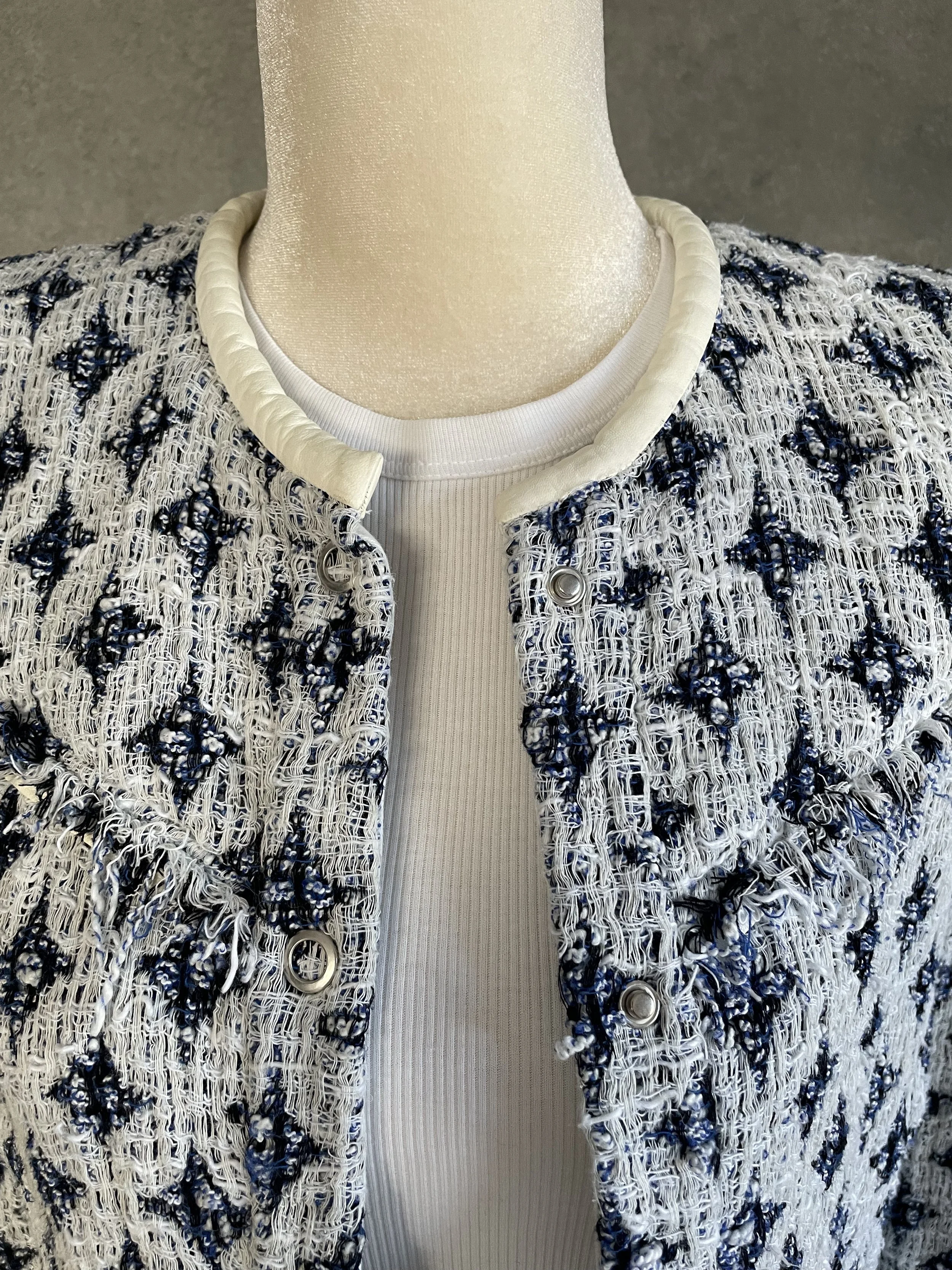 Close-up front view of the white leather trim collar and snap button hardware on the IRO tweed jacket.