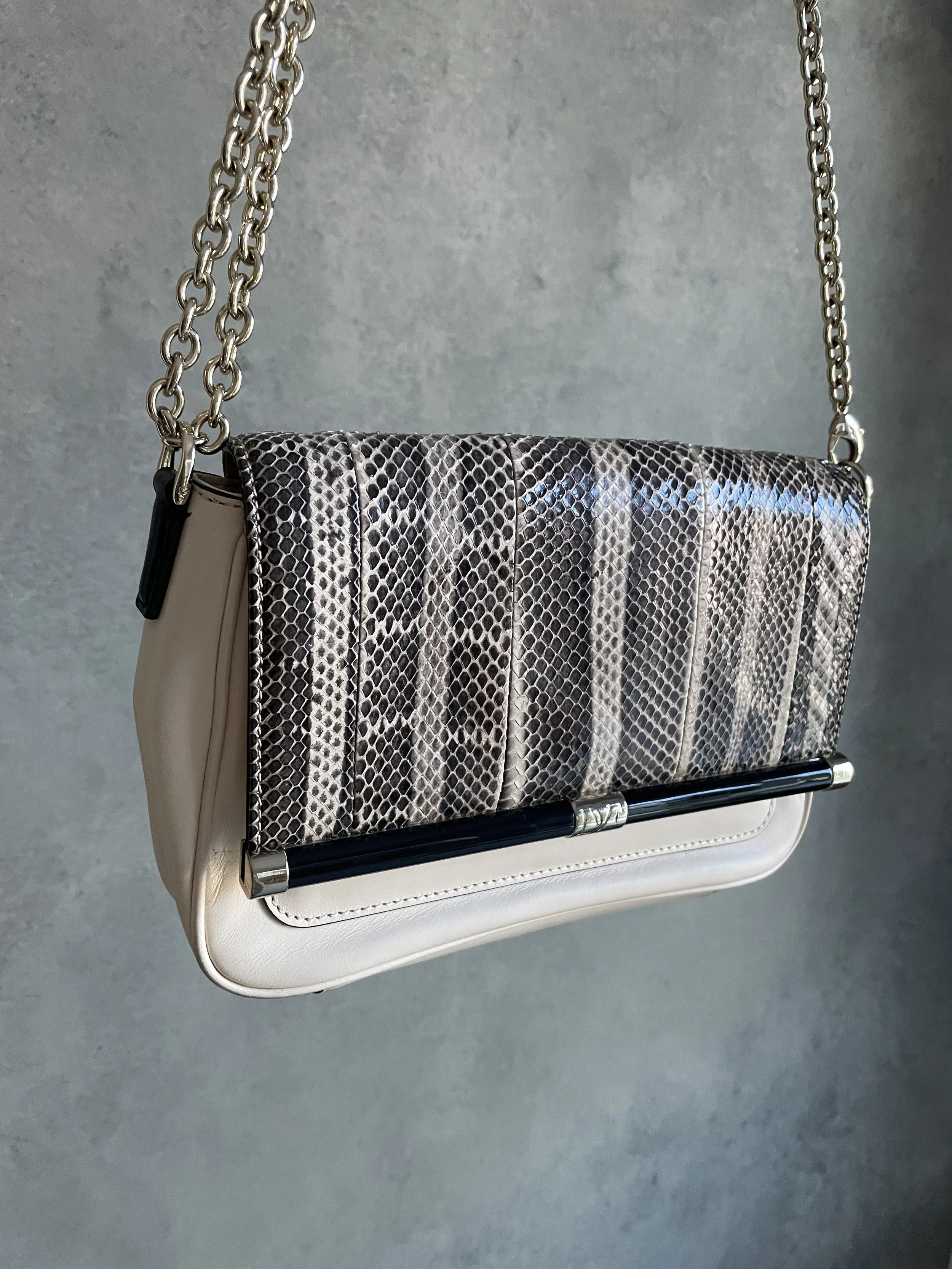 Angled view of the DVF 440 convertible handbag, showing the contrast between the snakeskin texture and smooth winter-white leather.