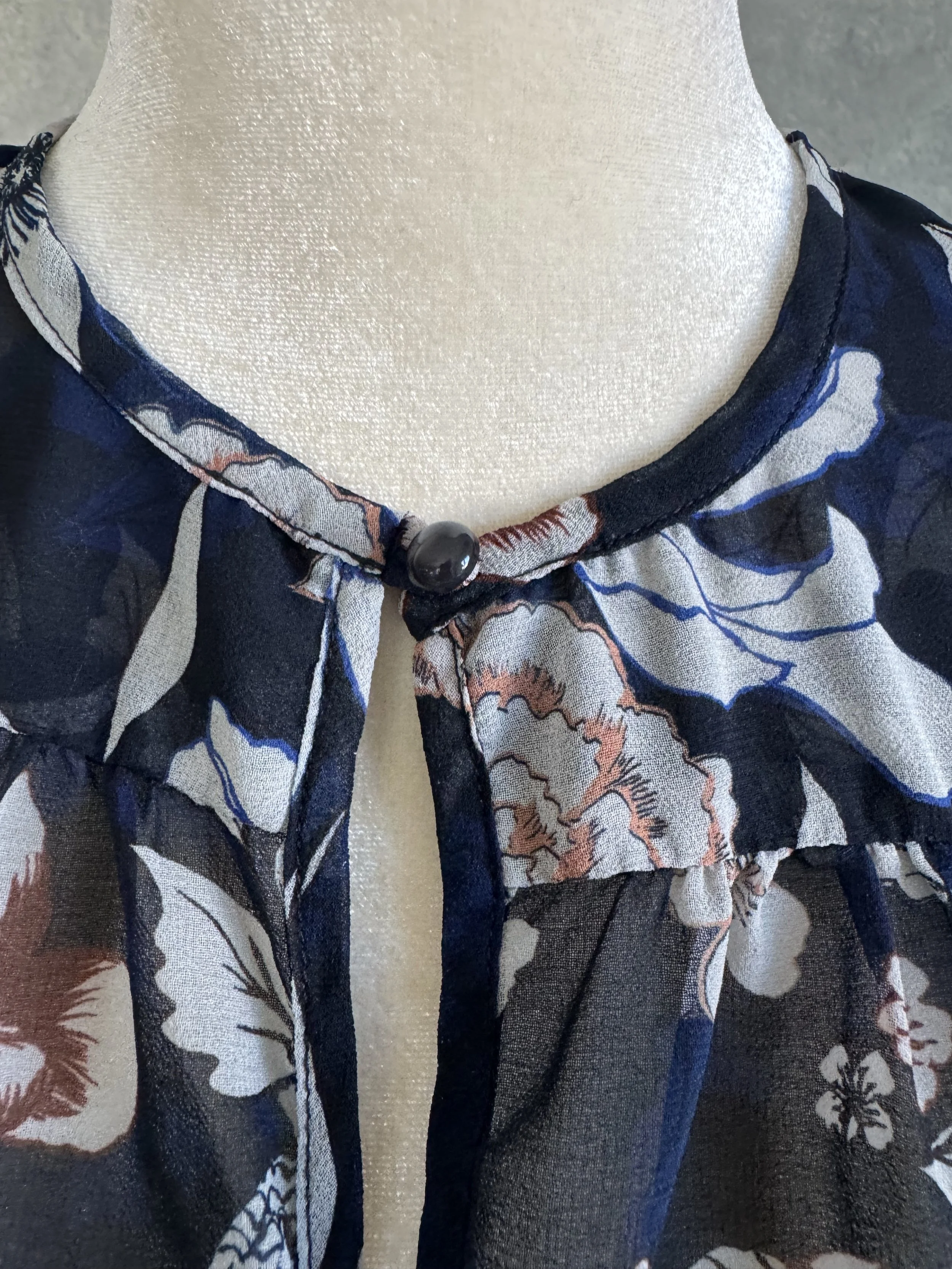 Close-up of the Gigue blouse, showcasing the intricate floral pattern in crisp white against a deep navy background.