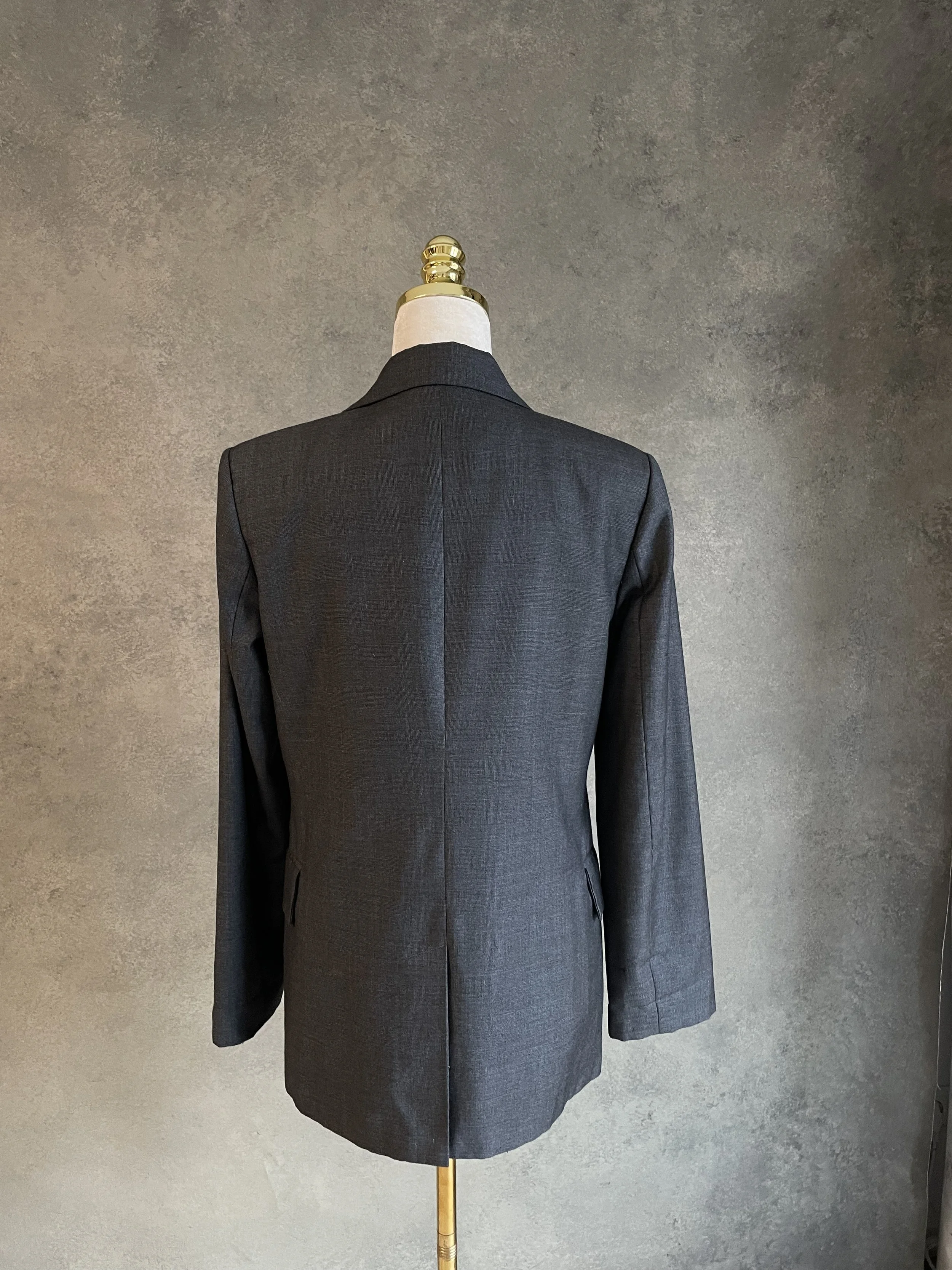 Full back view of the blazer on a mannequin, featuring the center back vent and structured back paneling.