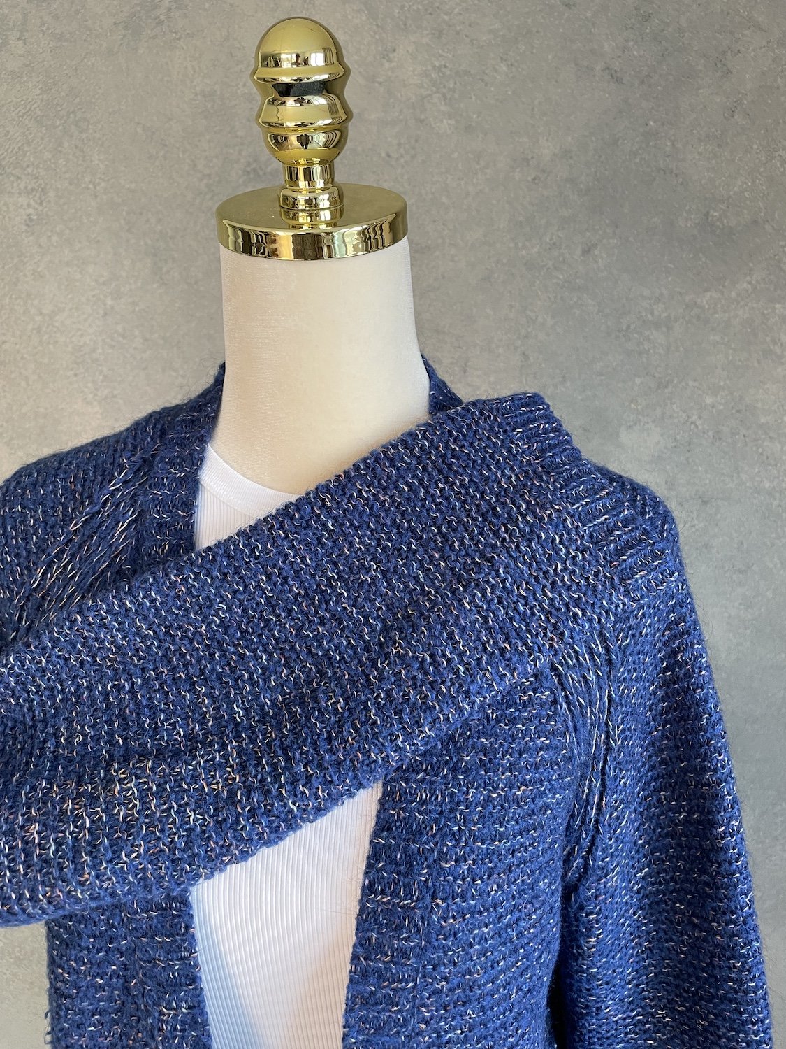 Close-up view of the sleeve folded across the front to highlight the soft textured melange yarn.