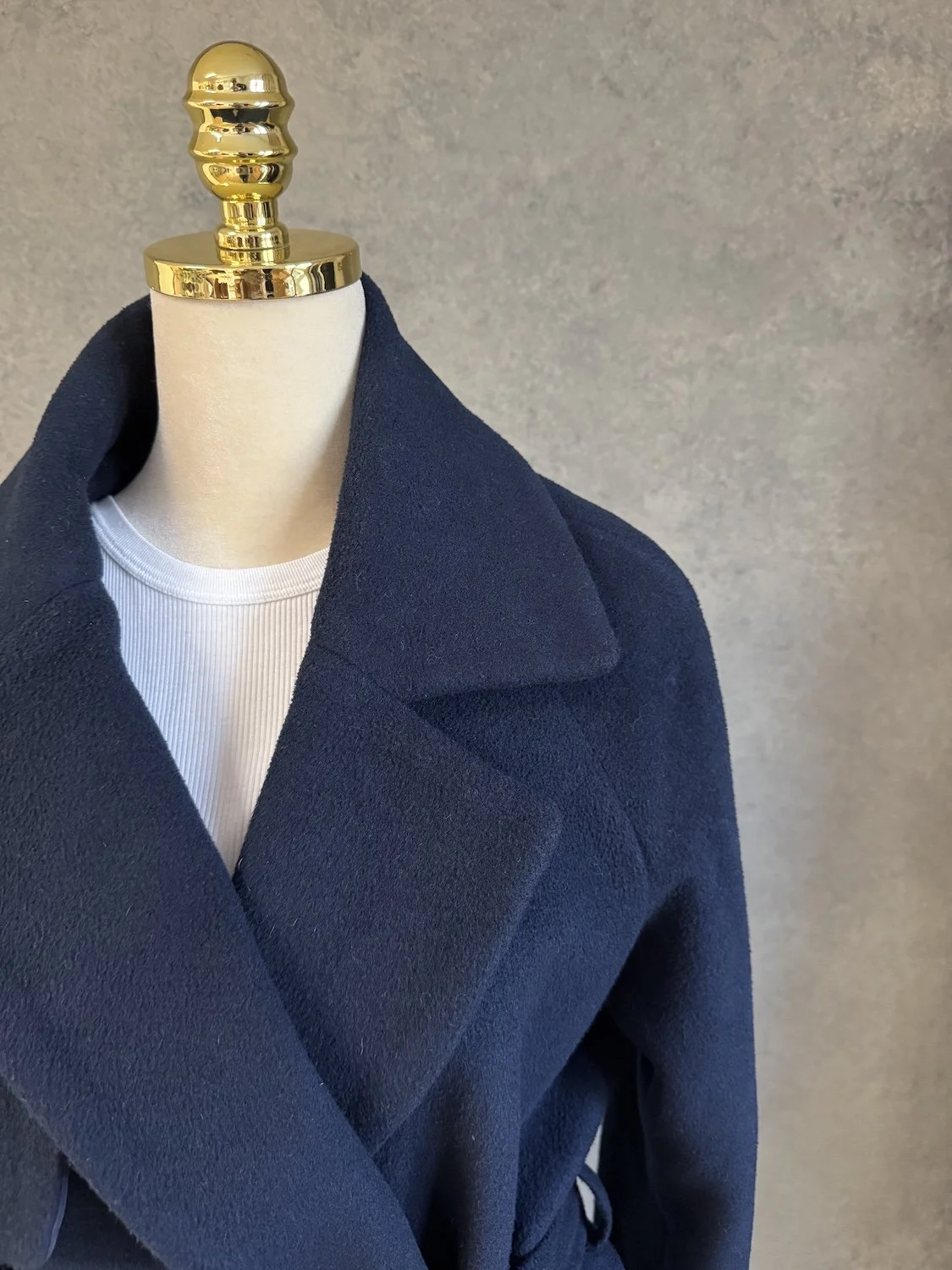 Close-up of the front lapel and collar area of the navy blue wool wrap coat.
