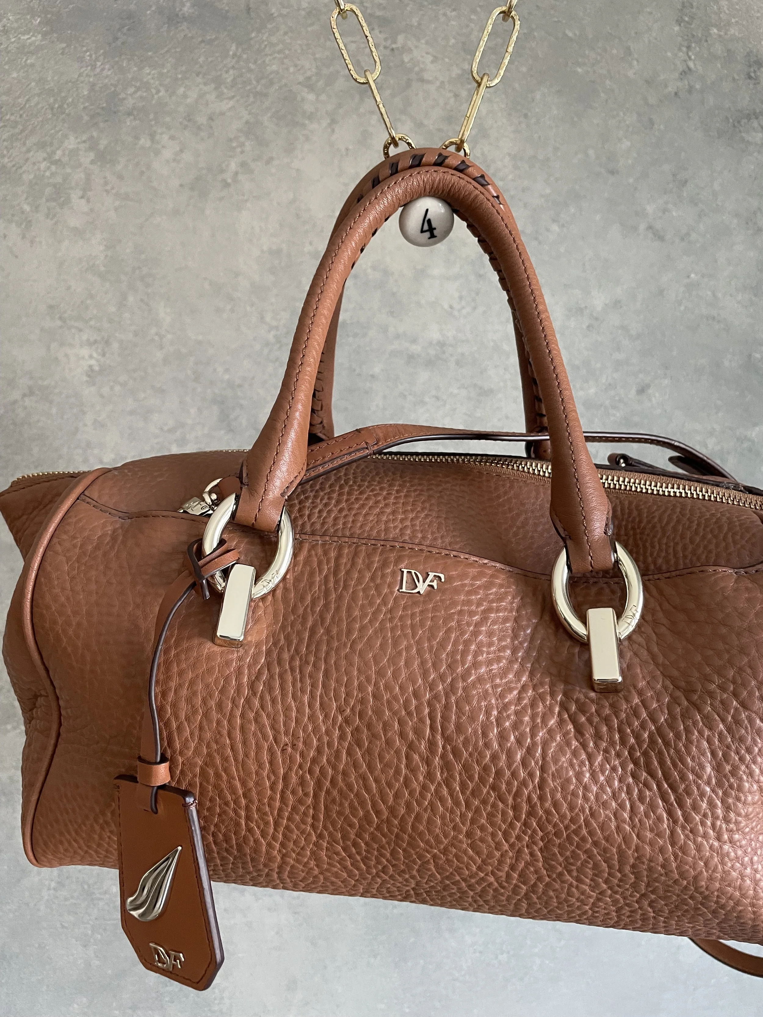 Front view of the DVF cognac leather tote, highlighting the gold hardware and branding.