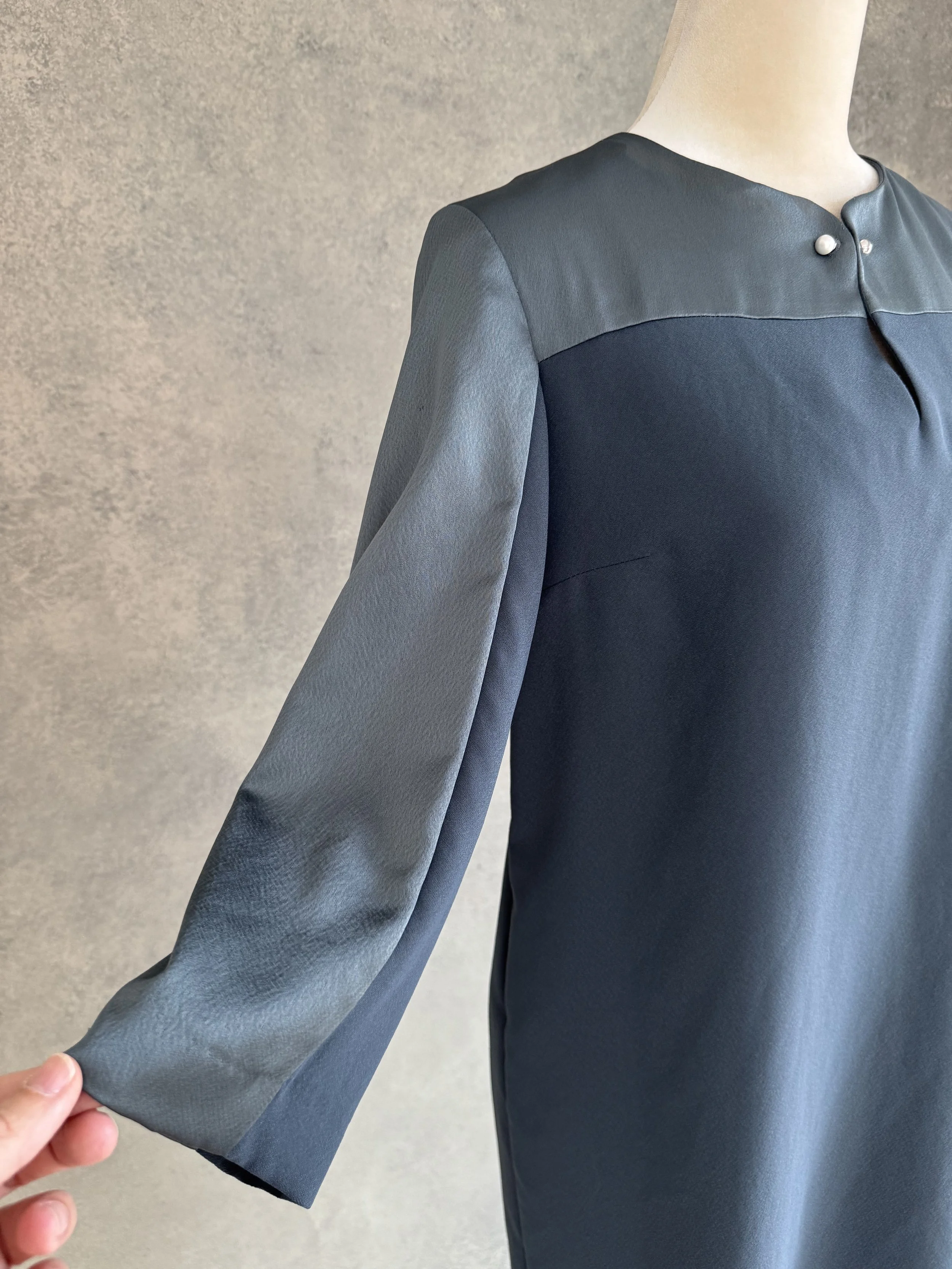 Gigue Kleid Detailaufnahme, Fokus auf den petrolgrünen Stoff und Seidenkragen