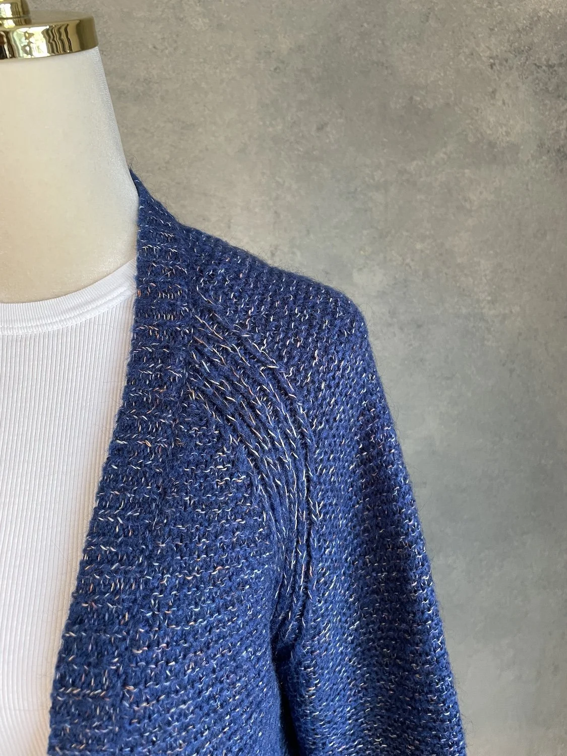Close-up of the shoulder and raglan seam featuring structured knit detailing on the Xandres cardigan.