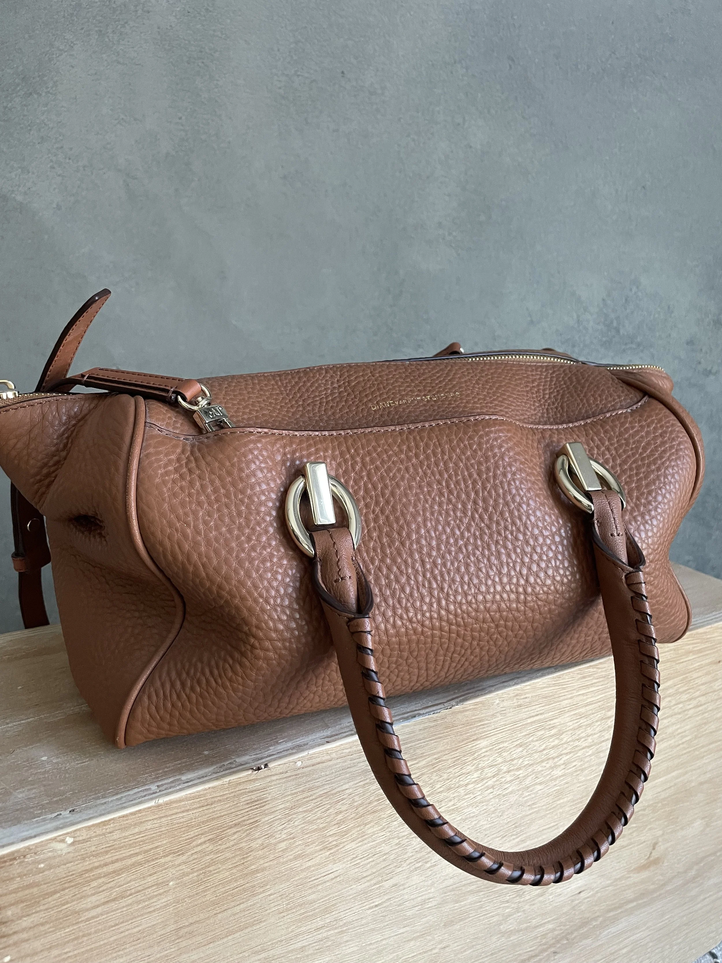 Three-quarter view of the DVF leather bag resting on a wooden surface