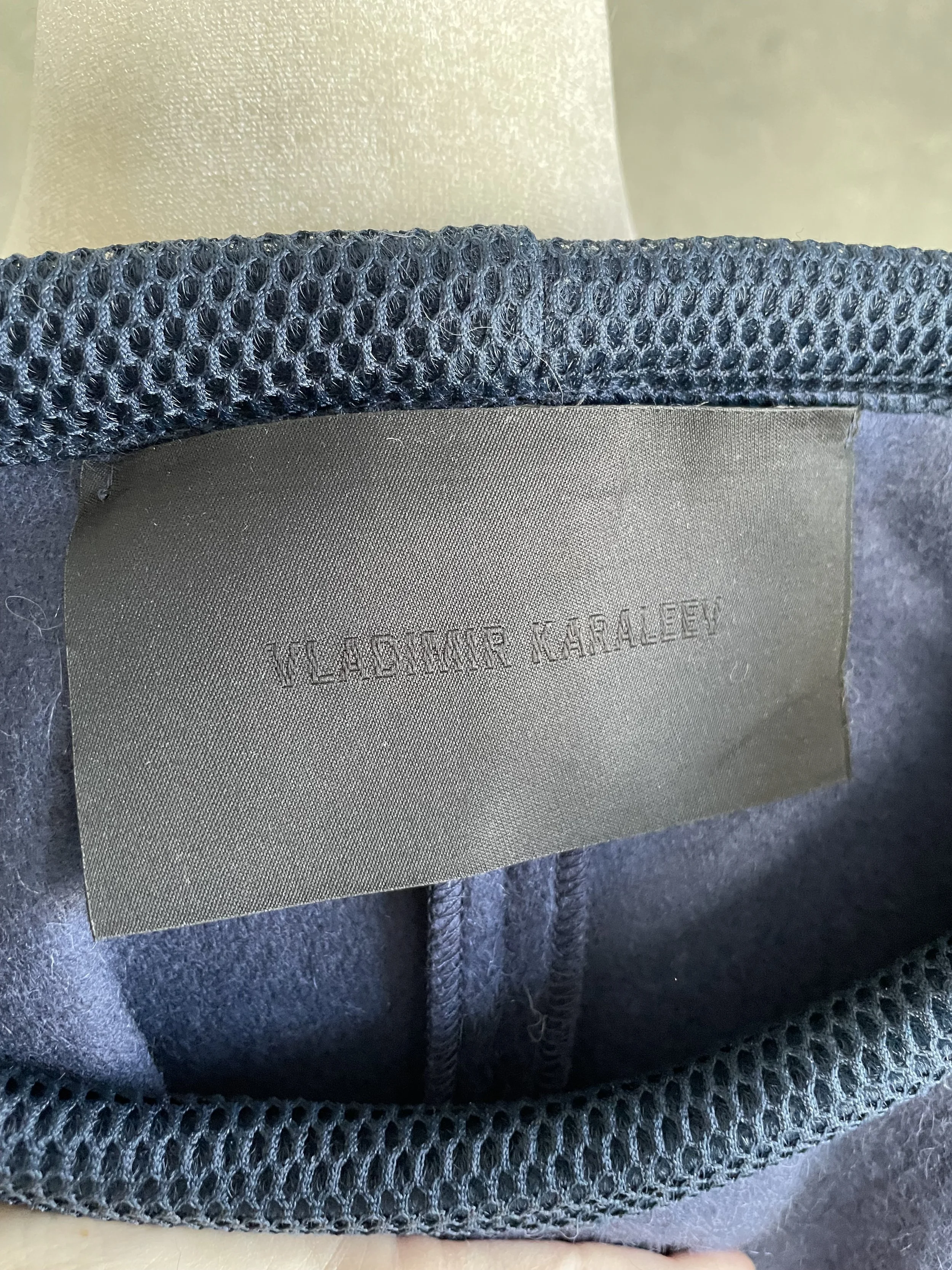 Close-up of the black internal brand tag reading "VLADIMIR KARALEEV" in clean, minimalist typography