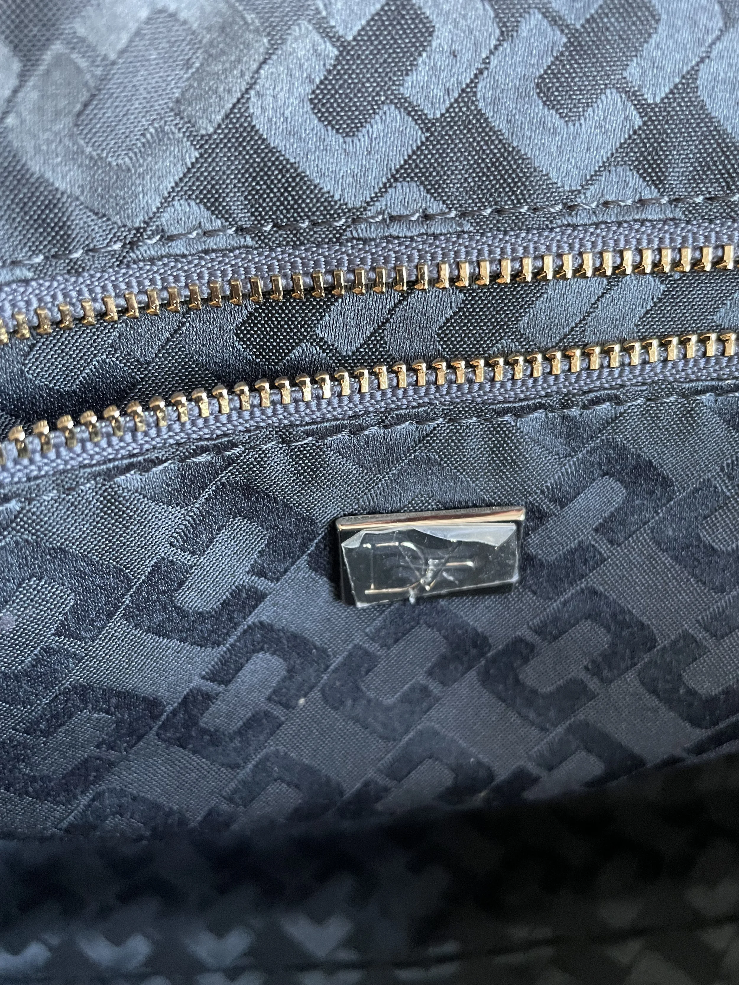 Detail view of the interior zippered pocket and DVF logo plaque inside the bag."