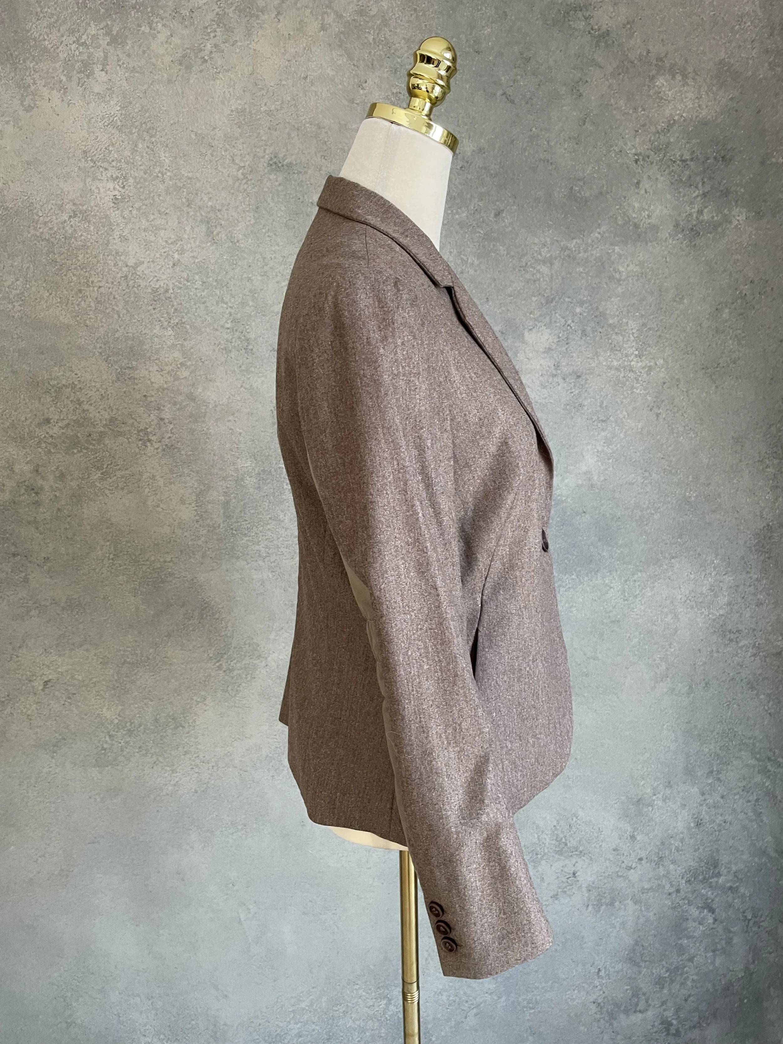 A side profile view of the blazer on the mannequin, clearly showing the length of the sleeve and the extent of the distinctive smooth side panels.
