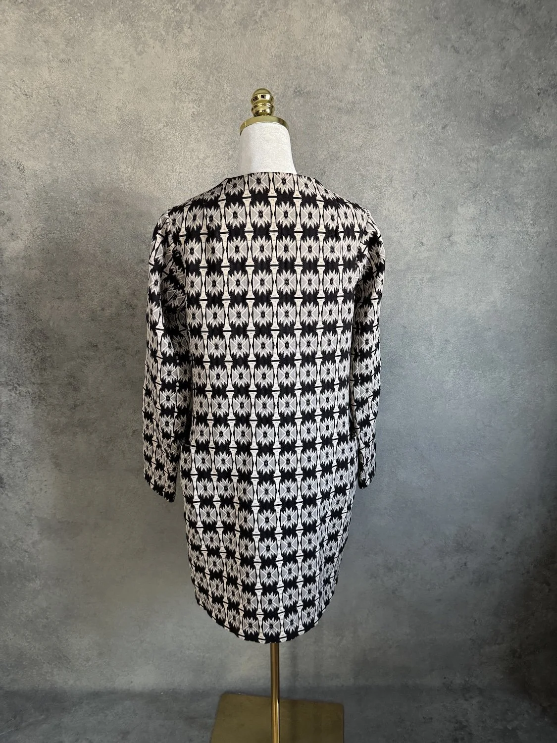 Close-up of textured black and beige geometric jacquard weave and collarless neckline