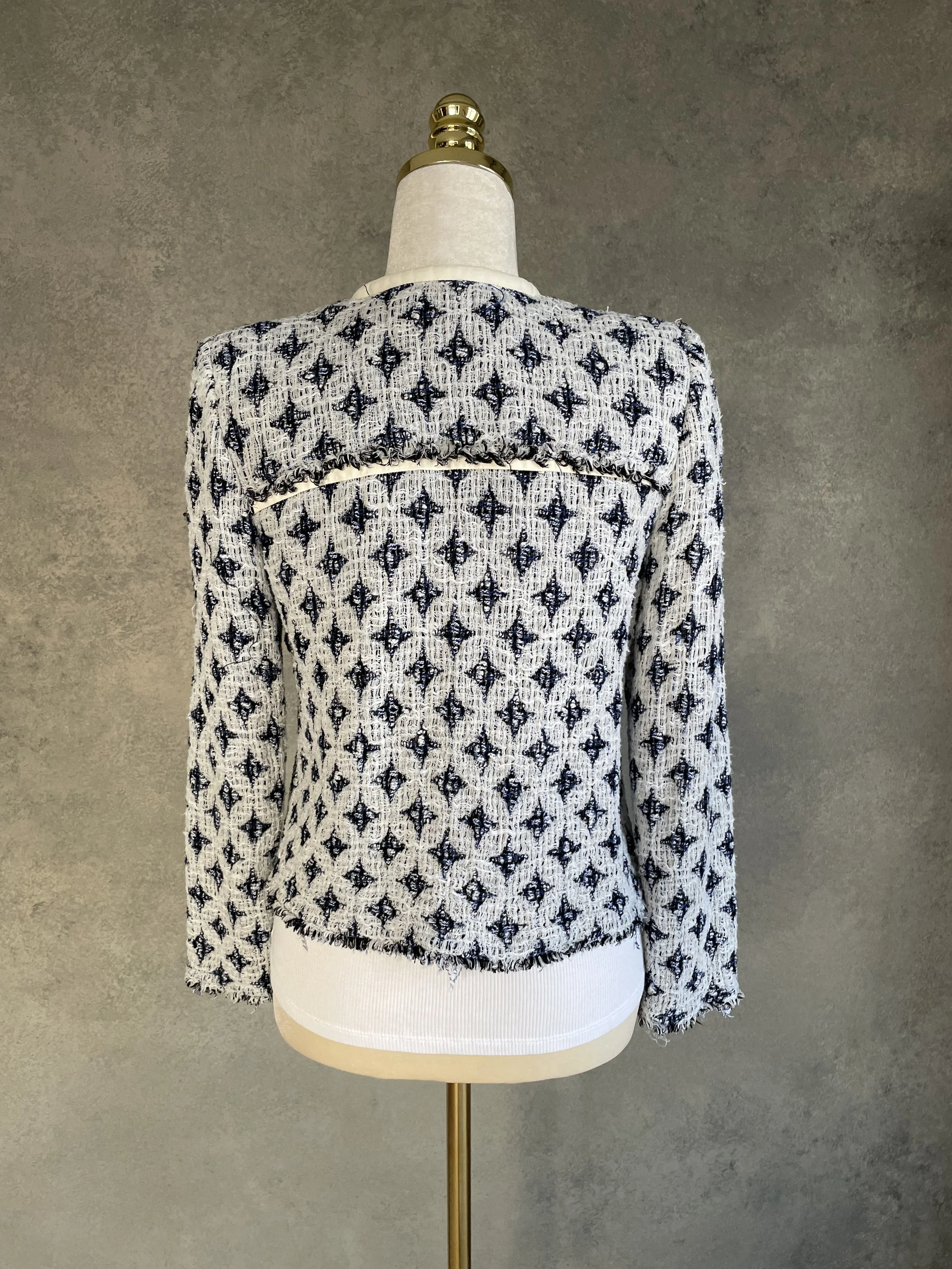 Back view of the IRO tweed jacket on a mannequin, displaying the horizontal leather trim detail across the back.