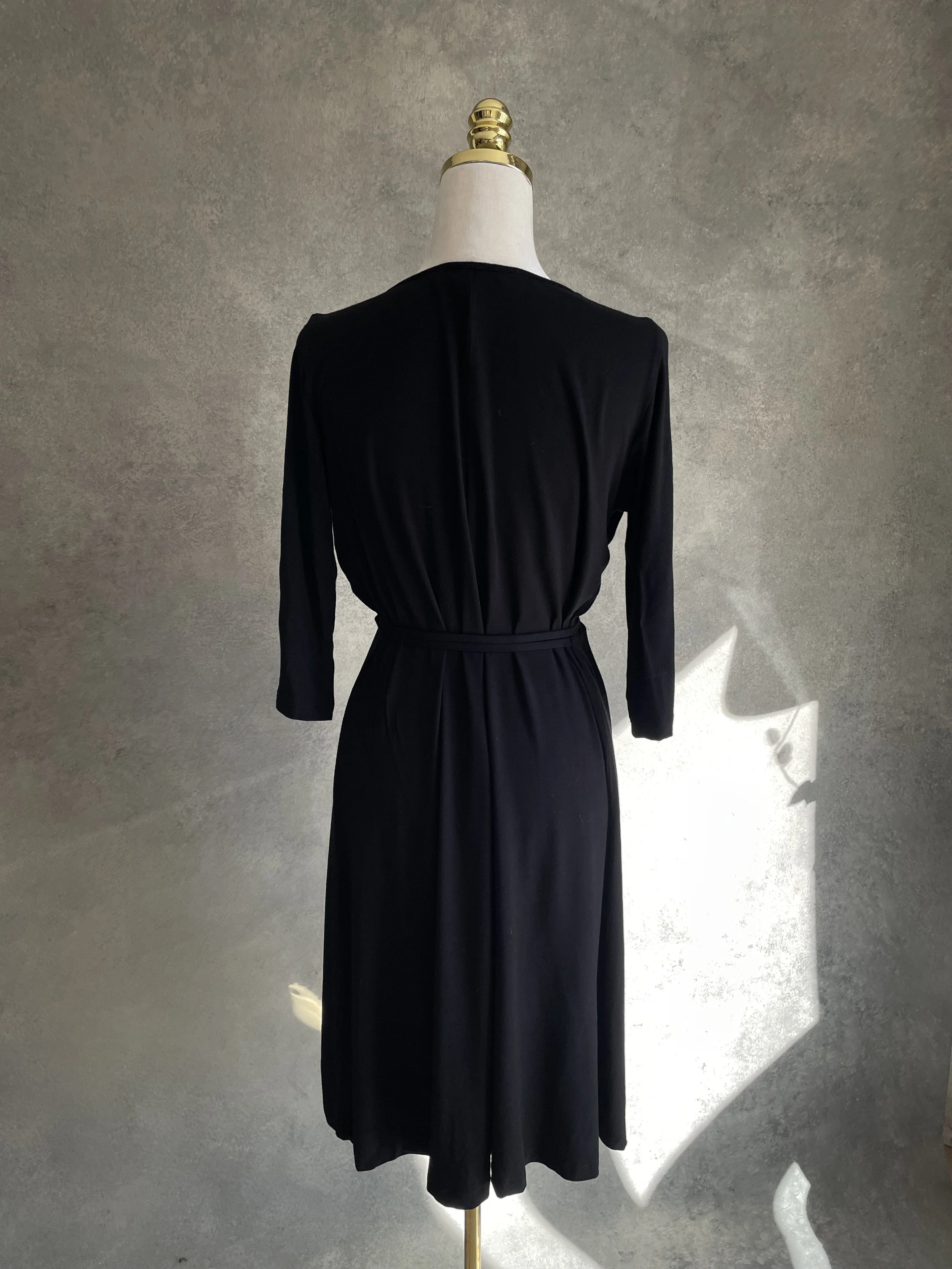 Full back view of the Scapa black jersey wrap dress displayed on a mannequin.