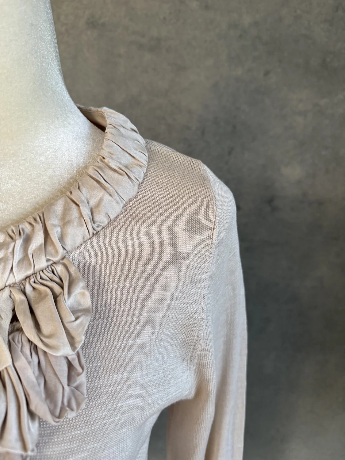 Detail shot showing fine beige mercerized cotton knit texture and silk neckline trim by GUSTAV