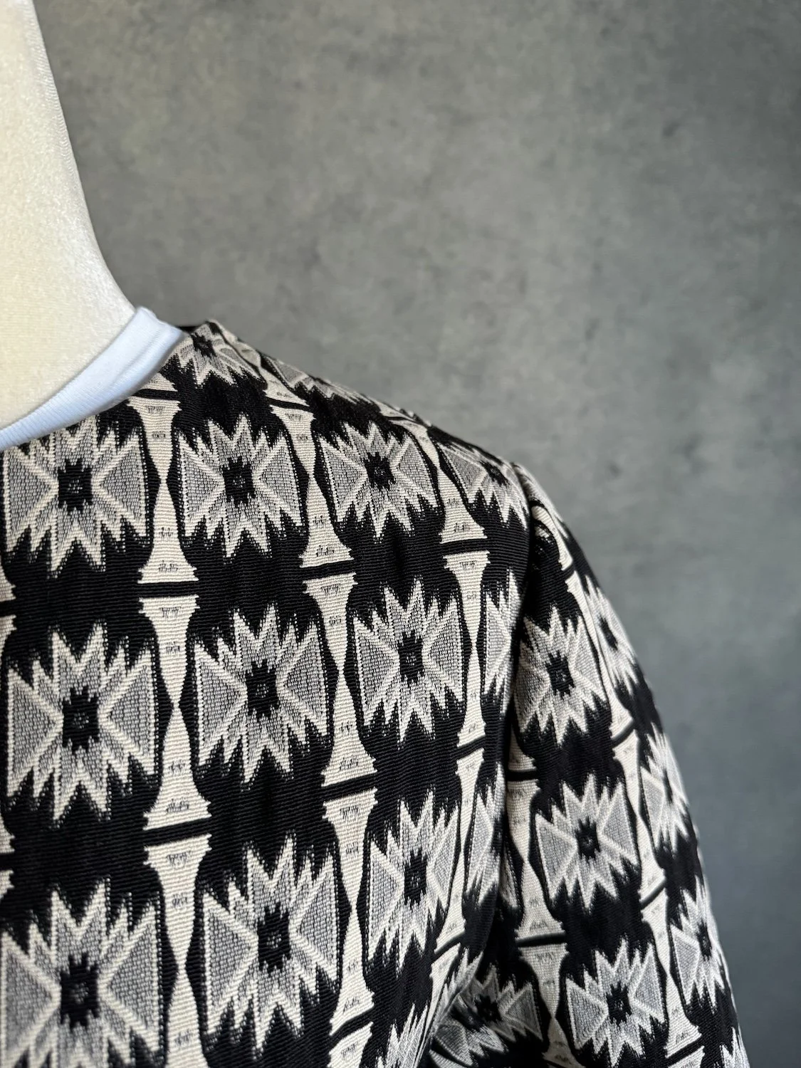 Full back view of Hoss Intropia black and beige geometric pattern coat on mannequin