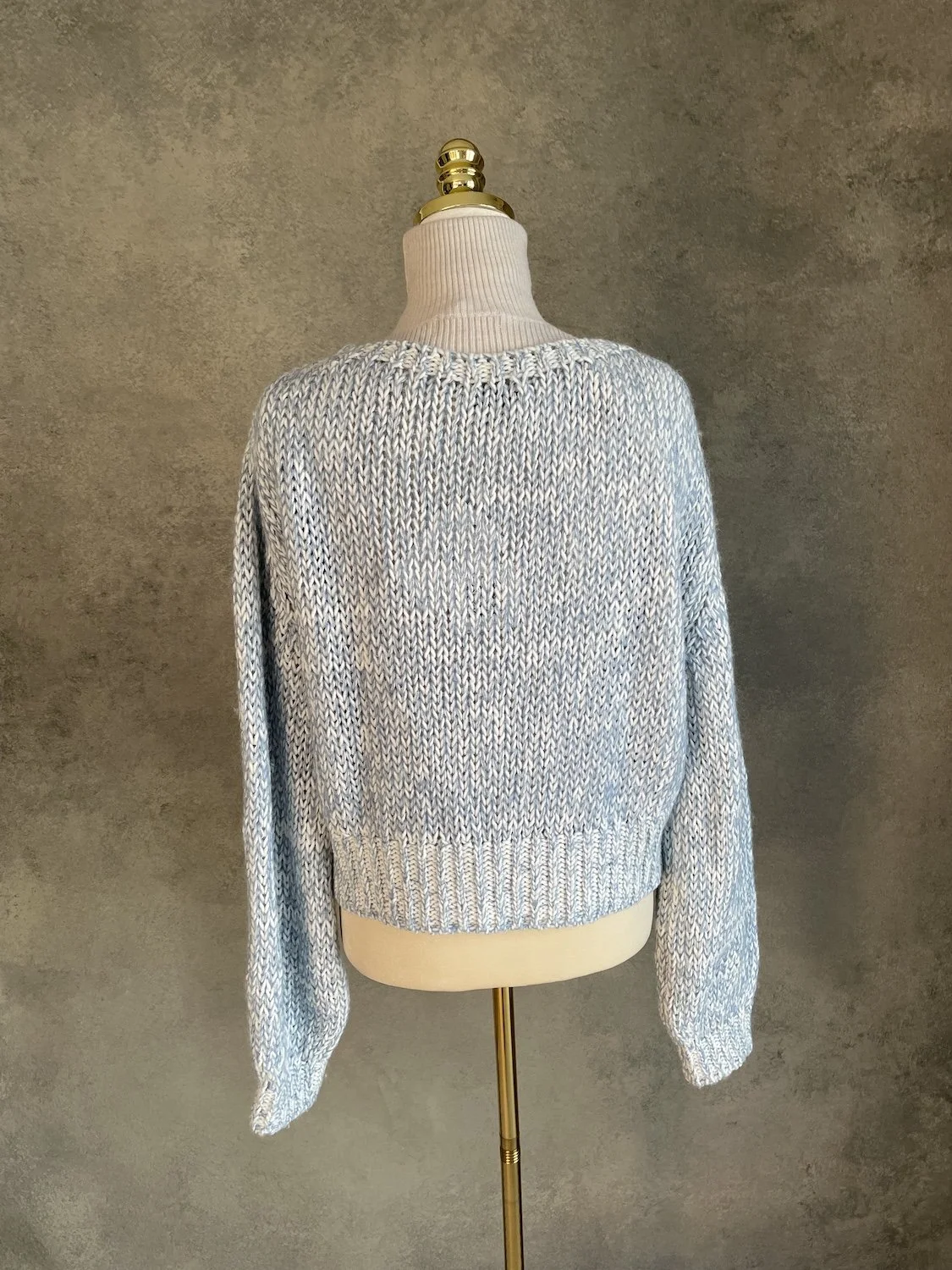 Back view of the Scapa Flow ice-blue melange sweater showing the consistent open-knit texture and ribbed hem.
