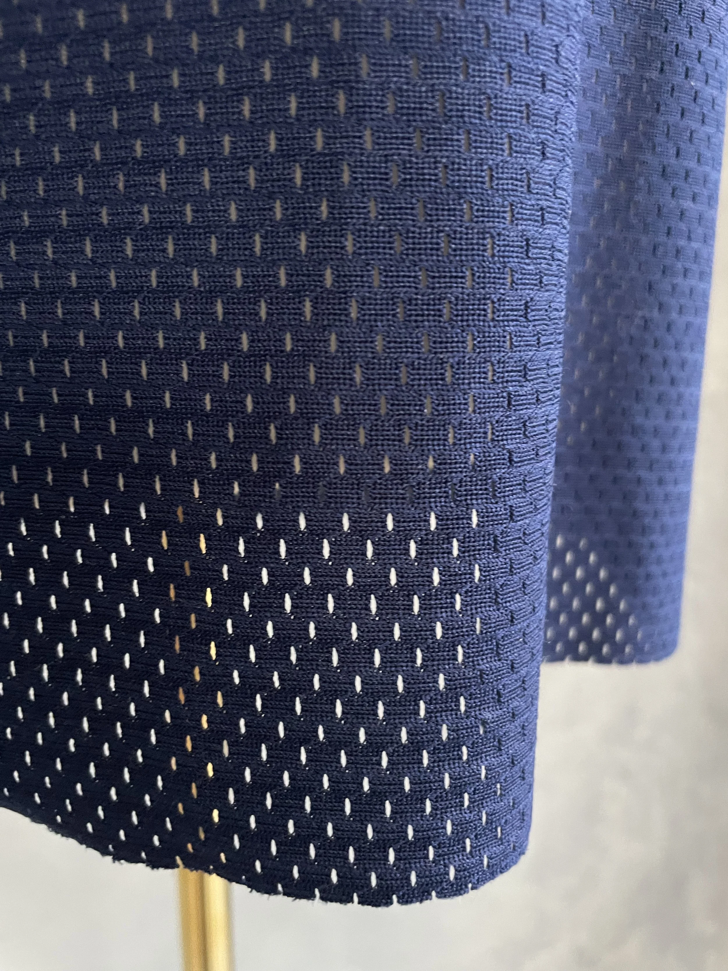 Close-up of the mesh-like fabric texture on the lower portion of the sweater.