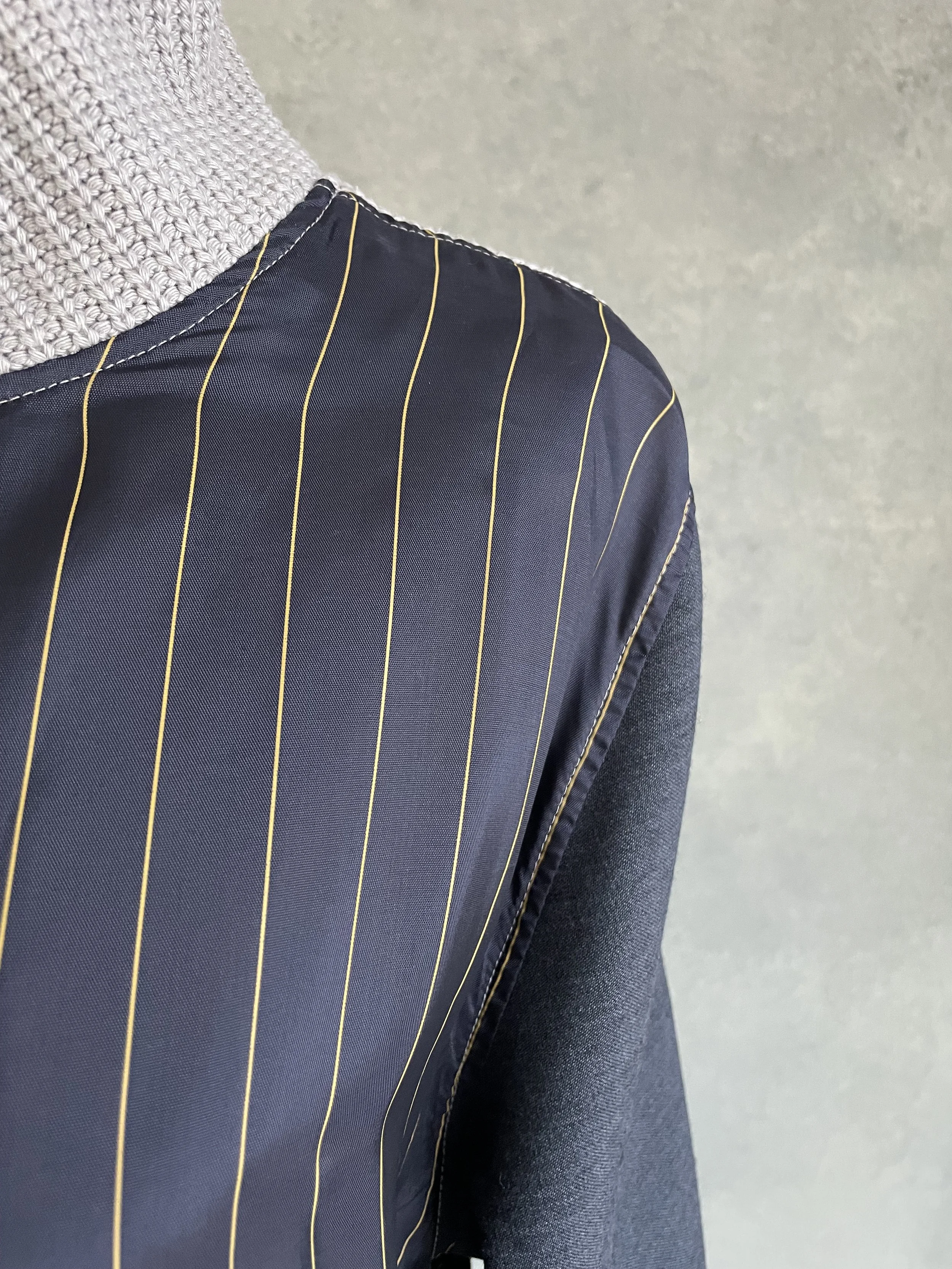 Detail shot of the seam construction where the gold-pinstriped navy fabric meets the grey knit on the Vladimir Karaleev sweater.