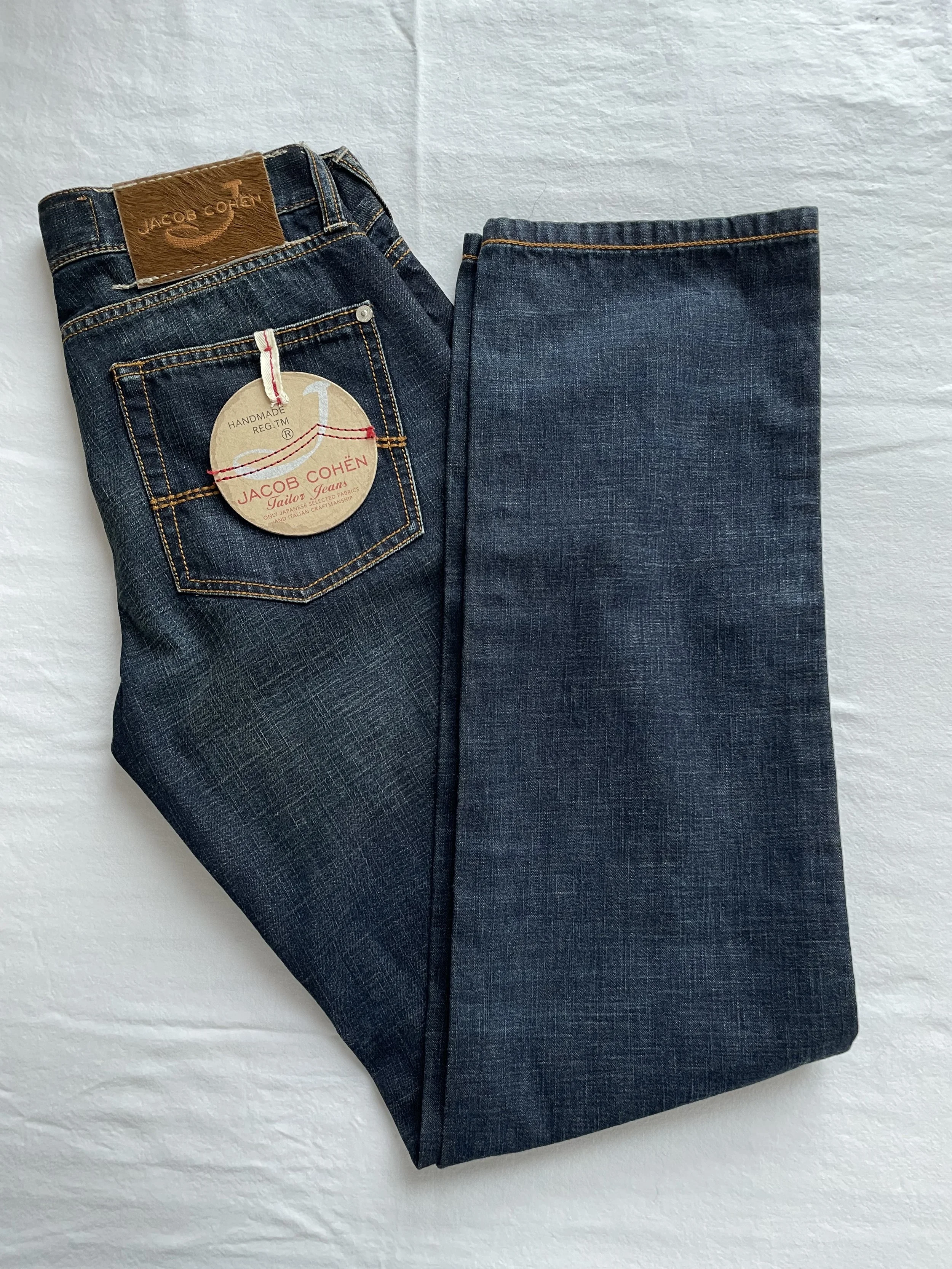 Flat-lay style hanging shot of Jacob Cohën dark blue jeans, showing the straight-leg silhouette and premium denim finish.
