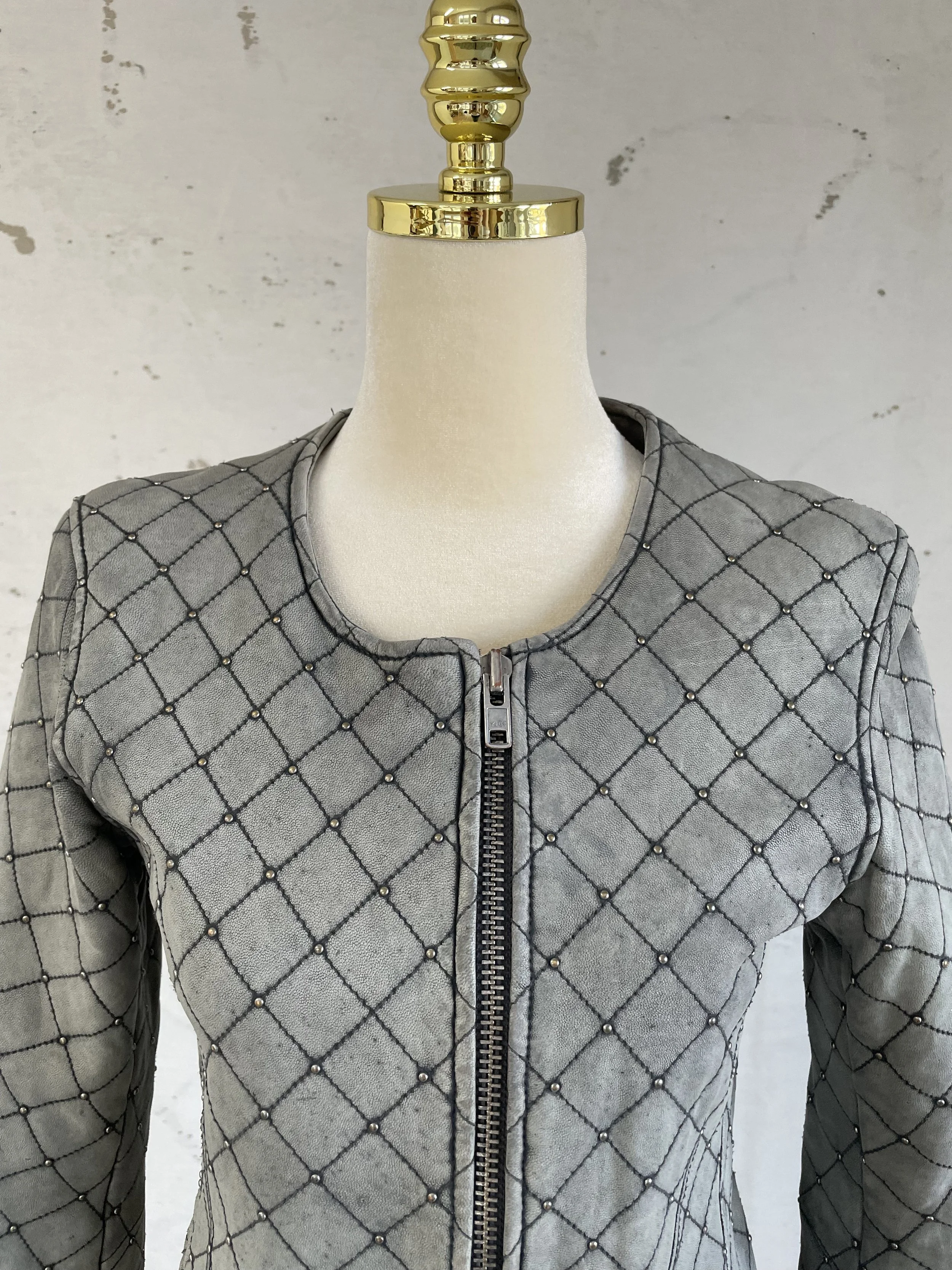 Macro shot of the Iro jacket’s smoky grey leather, highlighting the diamond-quilted stitching and metallic stud hardware