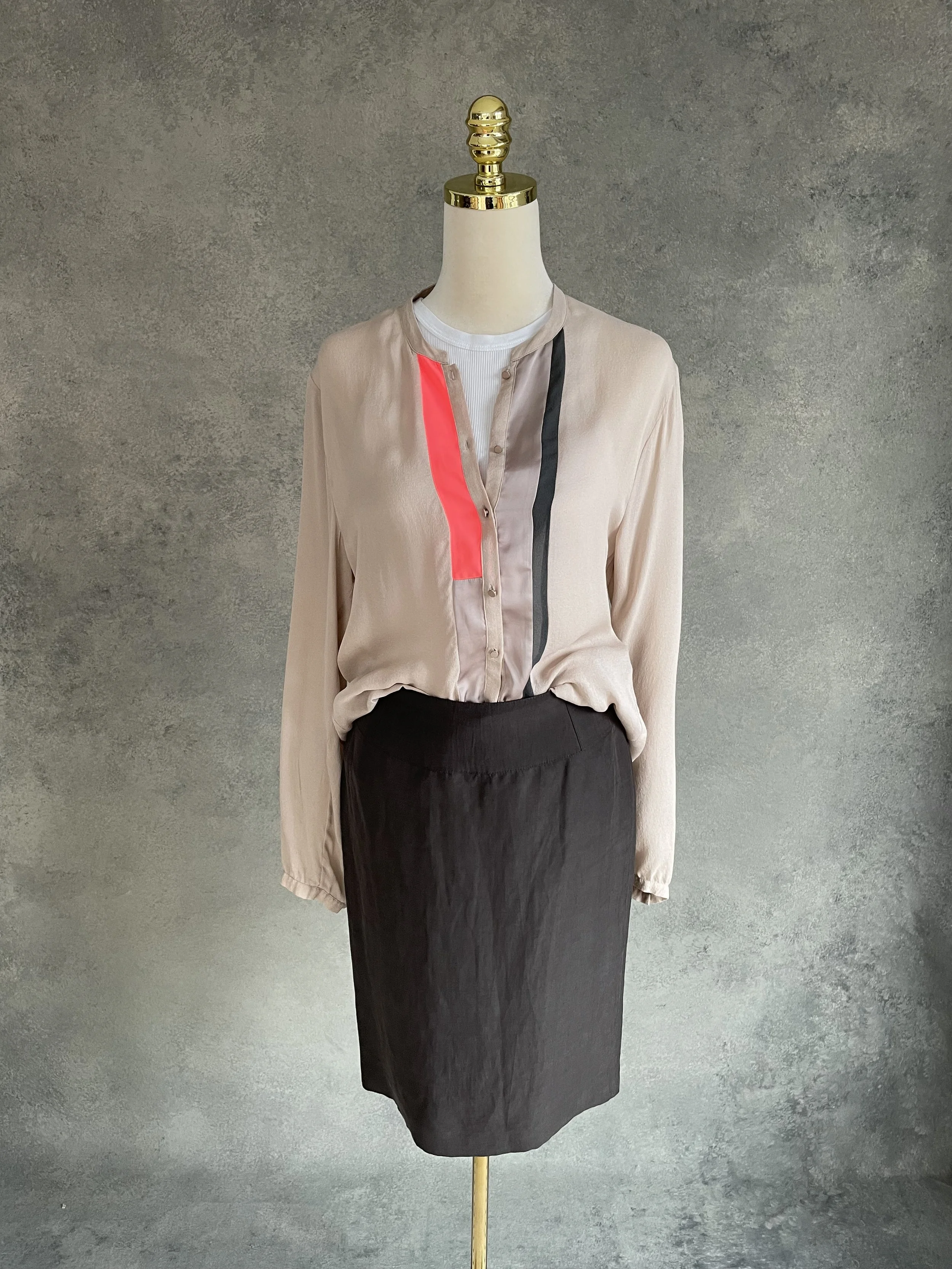 Mannequin wearing the Armani Collezioni brown skirt paired with a custom-made color-block blouse featuring neutral tones and a vibrant orange accent.