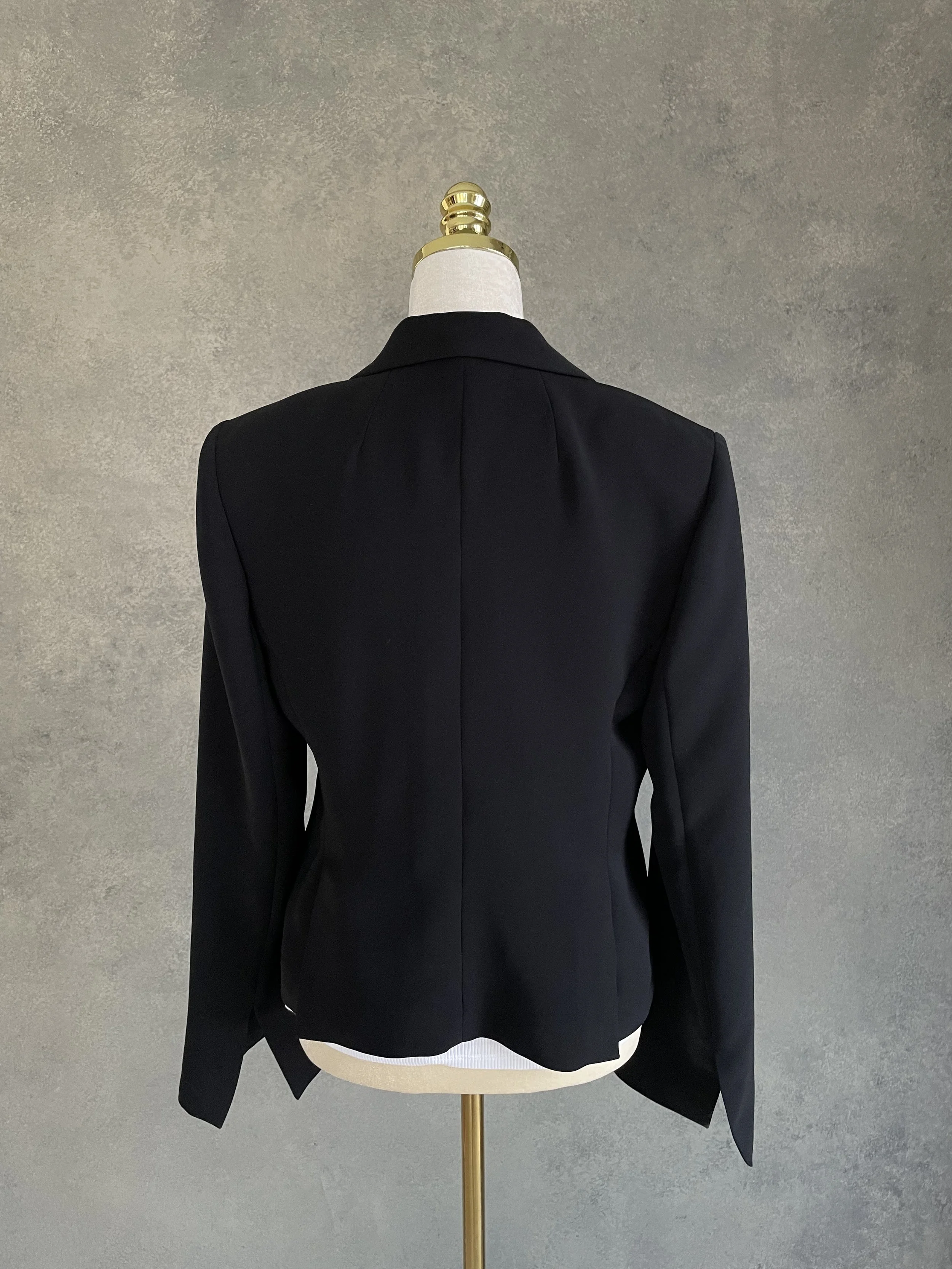 ABack view of the Archie Pell black blazer on a mannequin.