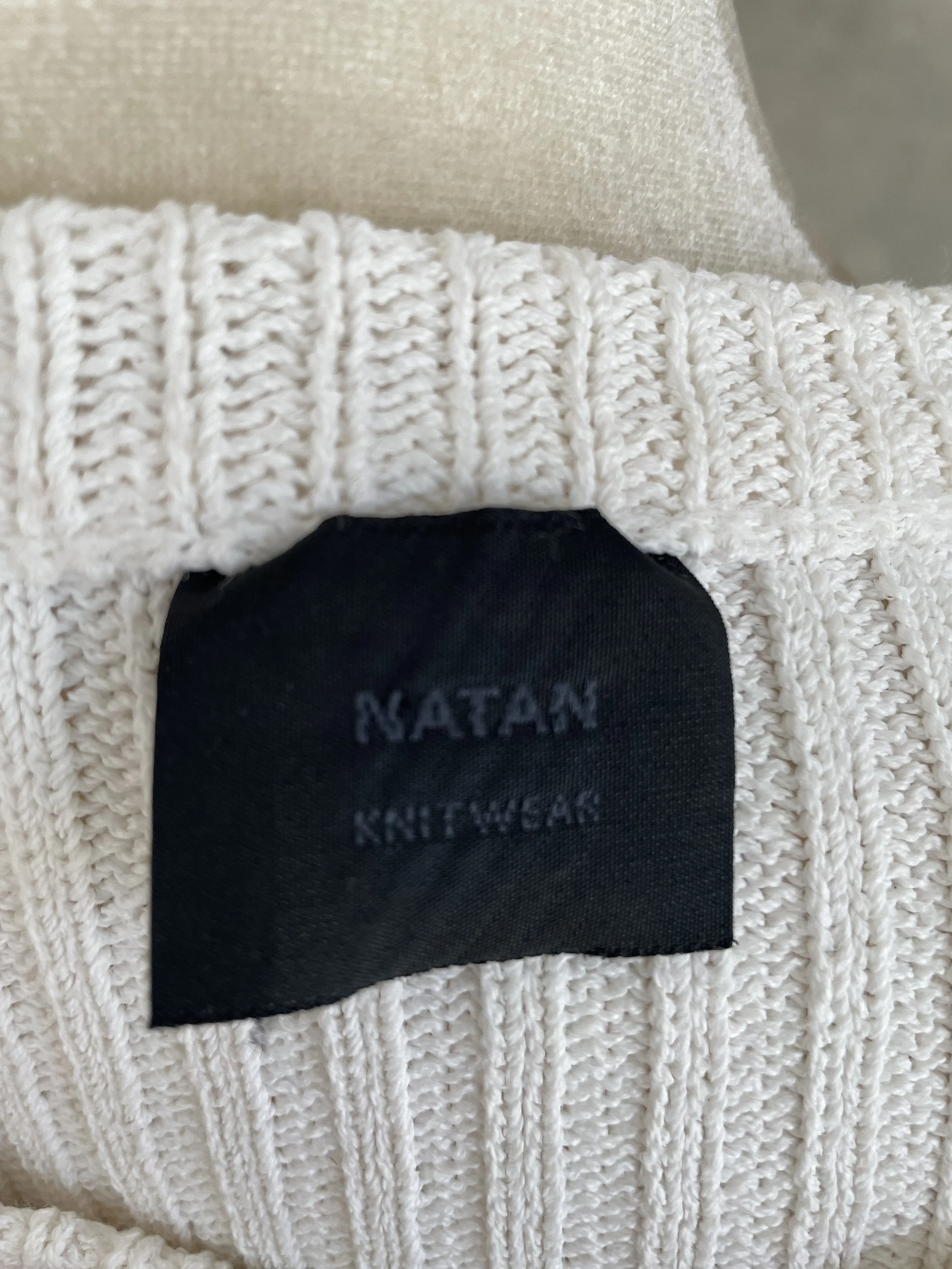 Detail shot showing the texture of the ribbed sleeve and shoulder area of the Natan knit top.