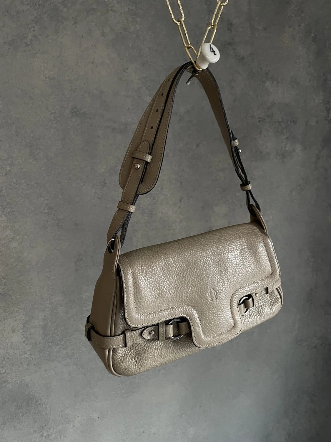 Angled perspective hanging shot of the beige pebbled leather Nobody baguette bag
