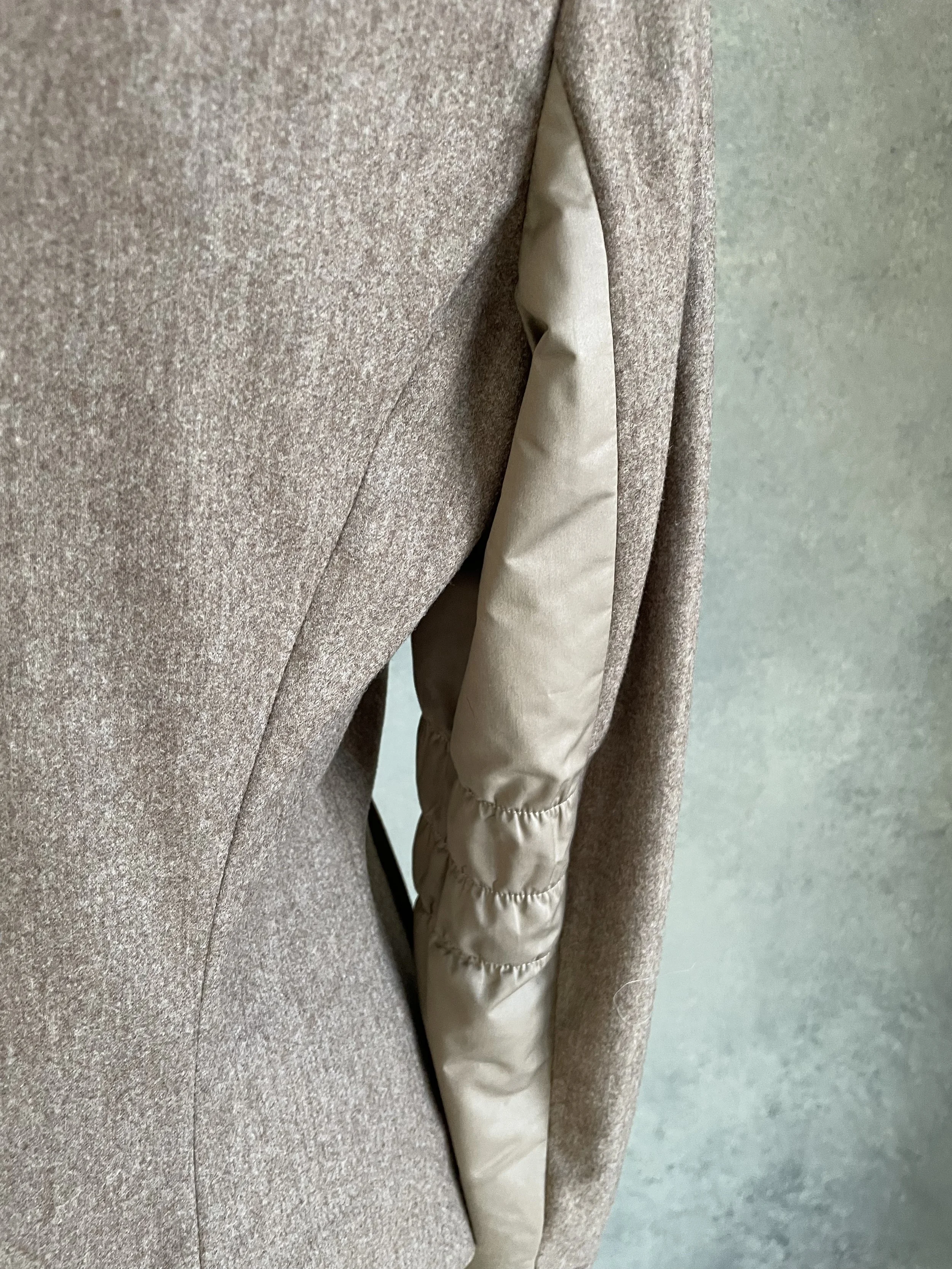 A detail shot focusing specifically on the bottom right corner of the blazer, showing the smooth texture of the side panel where it meets the tailored front and back wool section