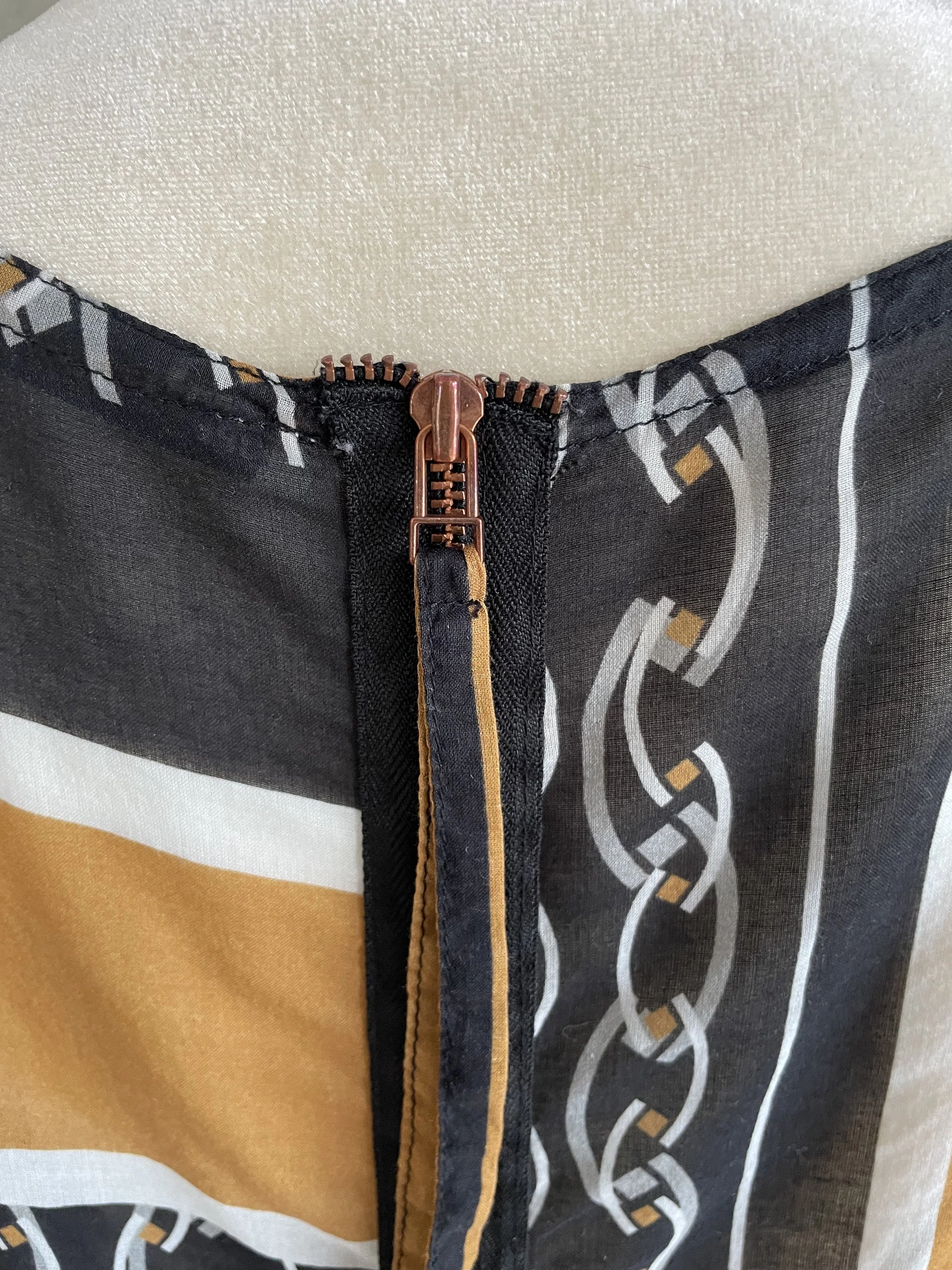 Detail shot of the metallic zipper pull on the back of the HOPE blouse.