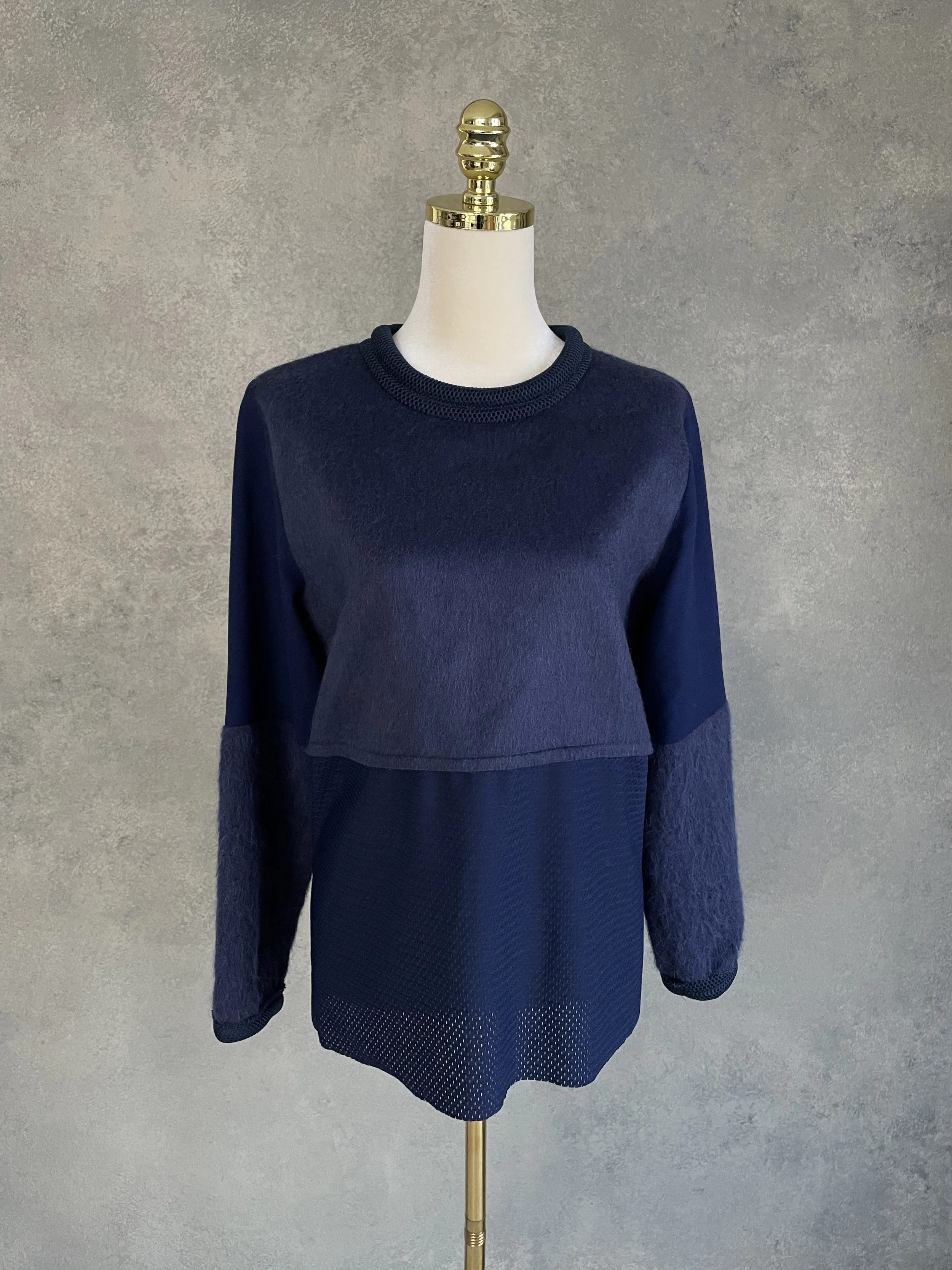 Mannequin displaying a deep navy Vladimir Karaleev sweater, showcasing a mix of textures including a smooth wool/mohair upper panel and a mesh-style lower panel.