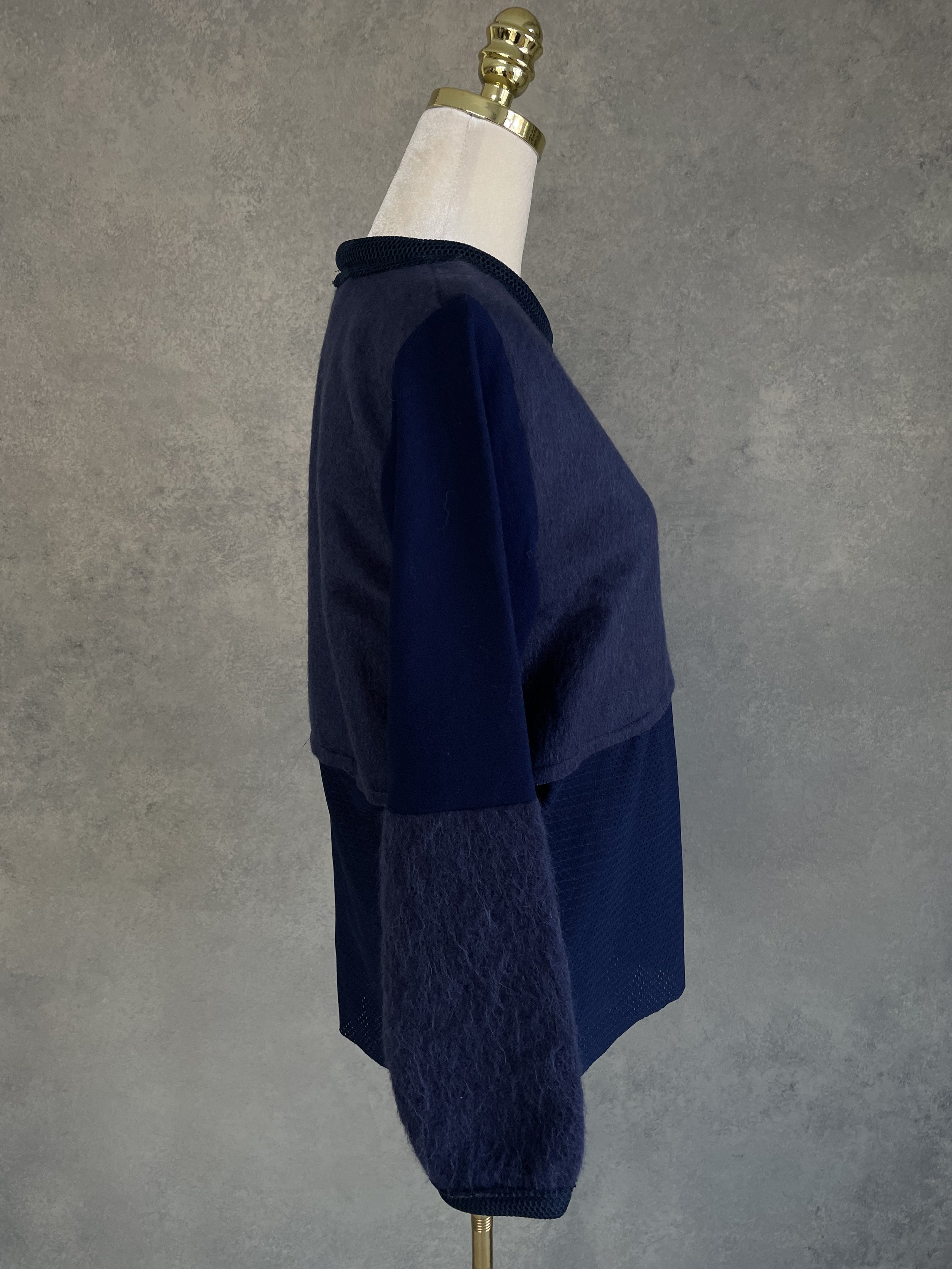 Side profile of the sweater, illustrating the structural fit and the contrast in material thickness.