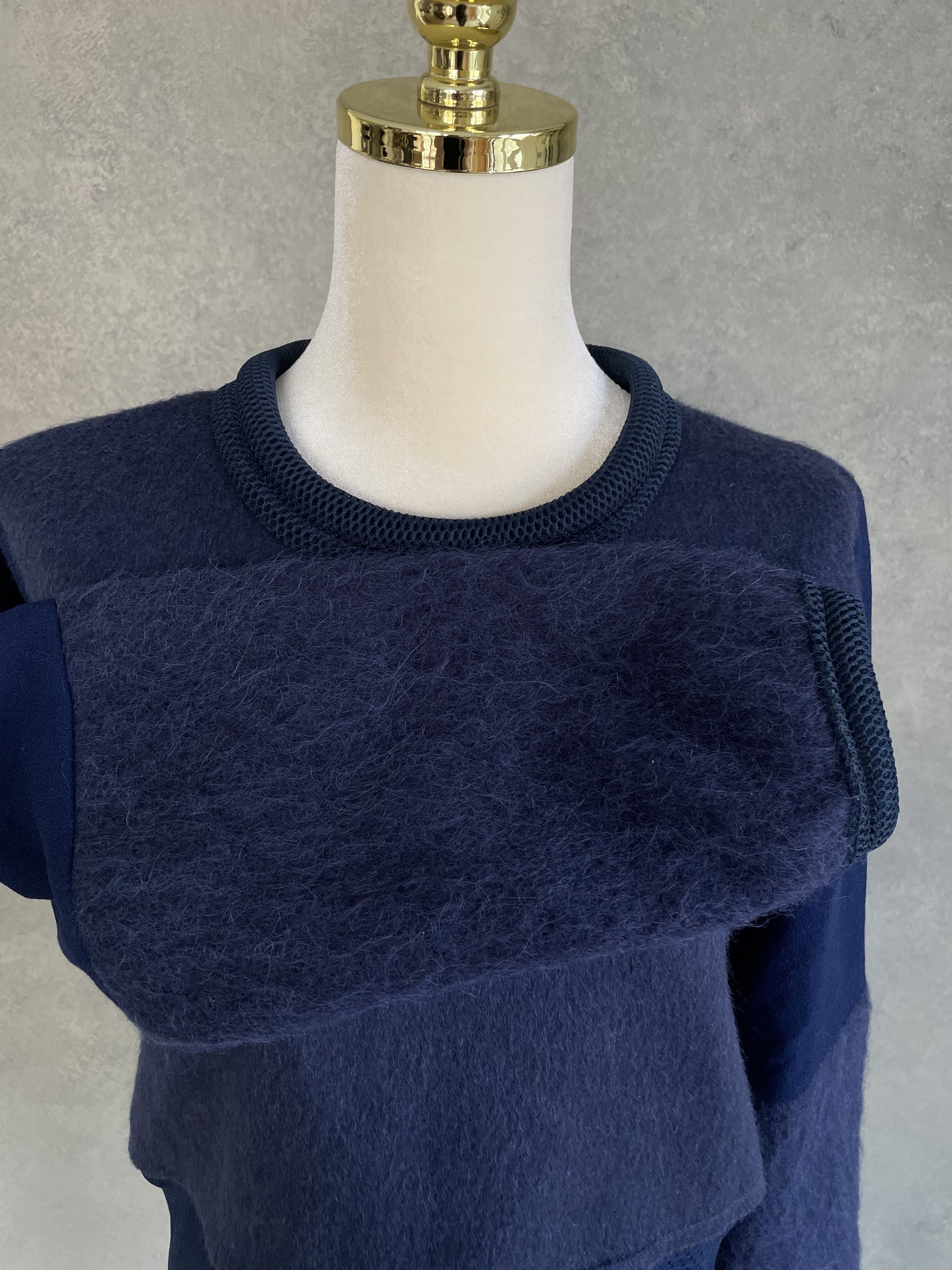 Front view highlighting the unique architectural seam where the fuzzy mohair-blend upper section meets the lighter, textured lower panel.