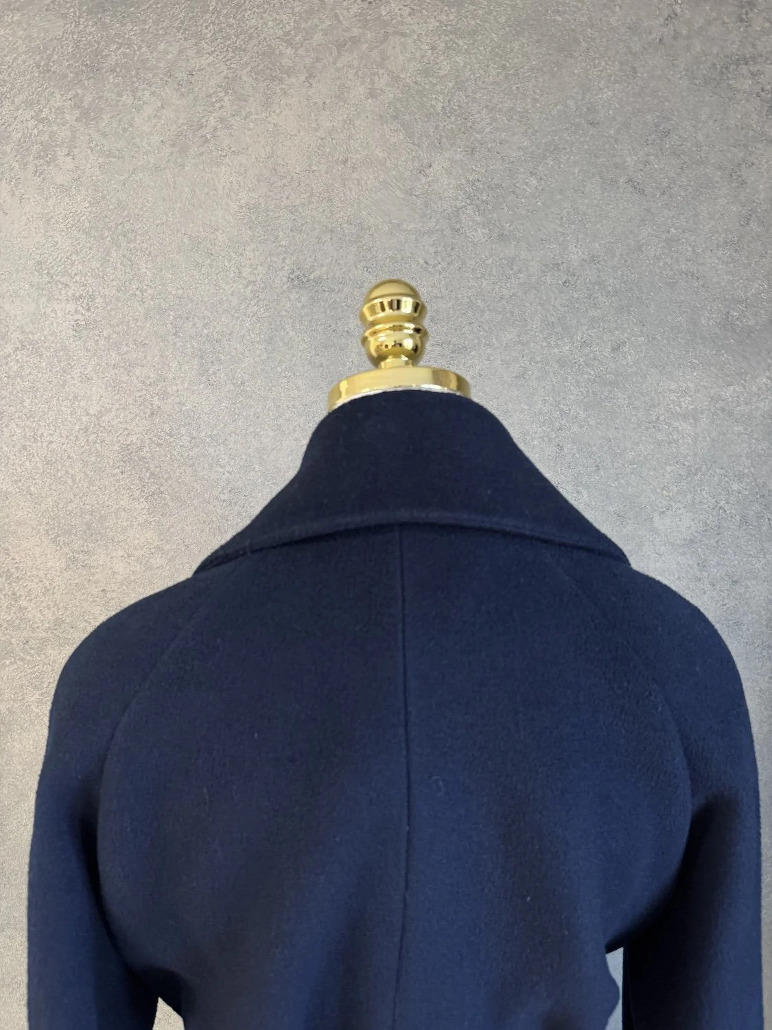 Close-up of the upper back yoke and shoulder seam detailing on the navy coat.