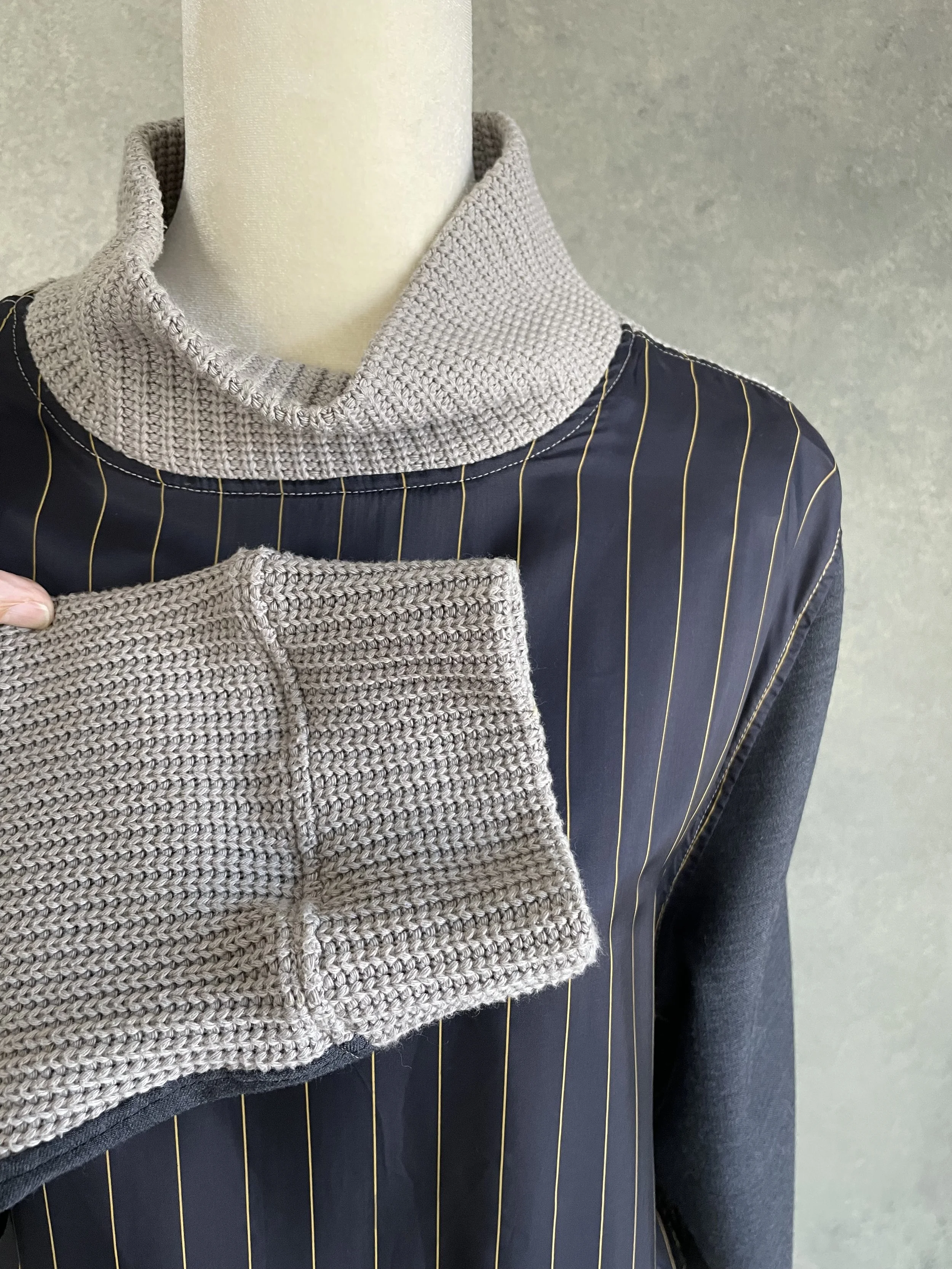 VClose-up of the textured grey knit sleeve cuff on a Vladimir Karaleev designer sweater.