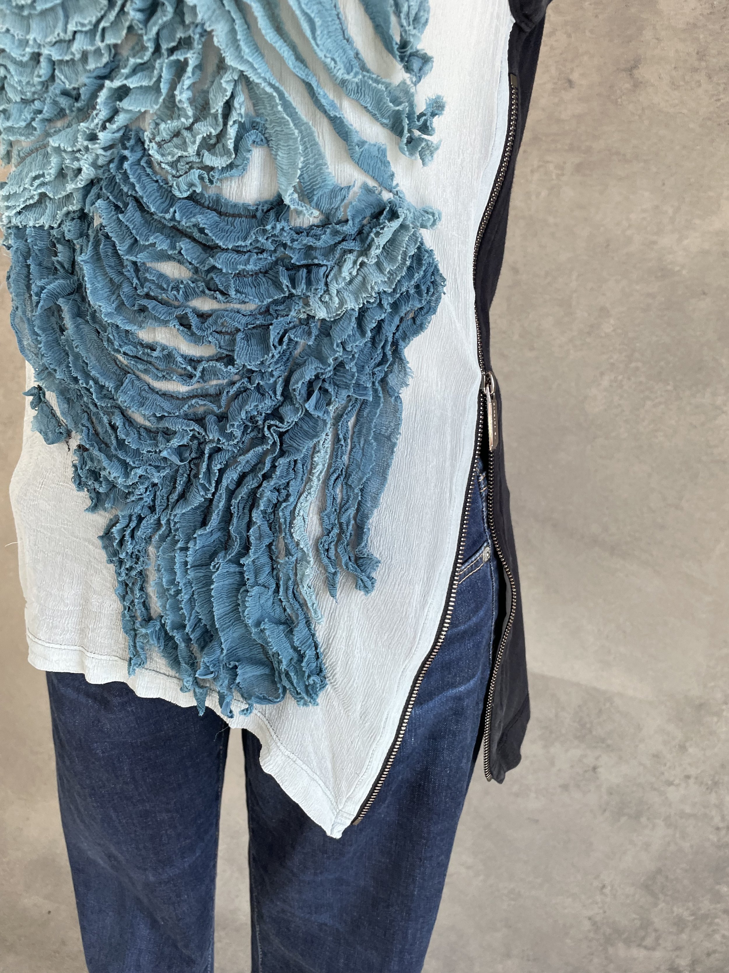 Close-up of the open side zipper detail on a person, creating an asymmetrical silhouette