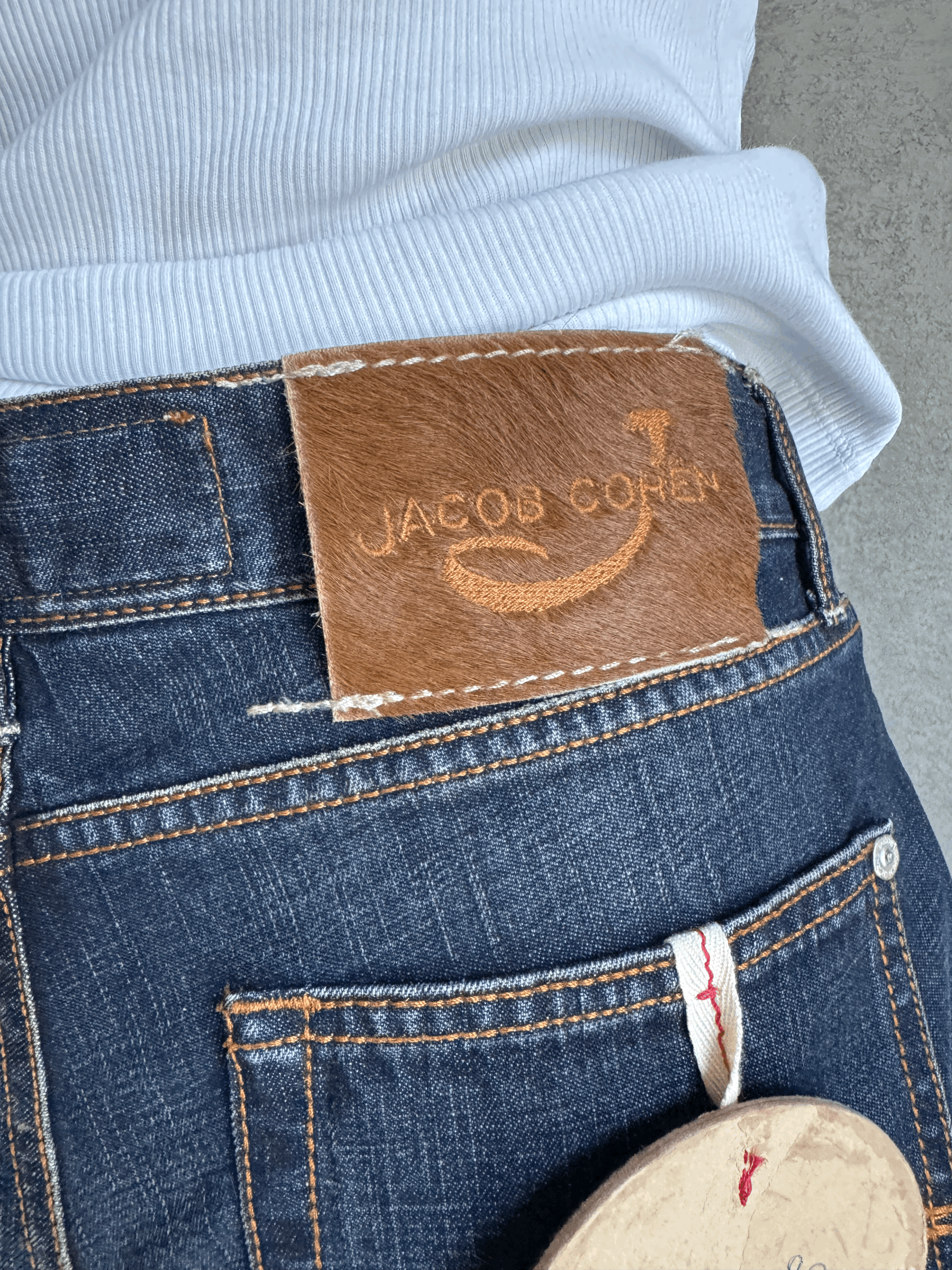 Close-up of the iconic Jacob Cohën pony hair patch on the back waistband of the dark blue Japanese denim jeans.