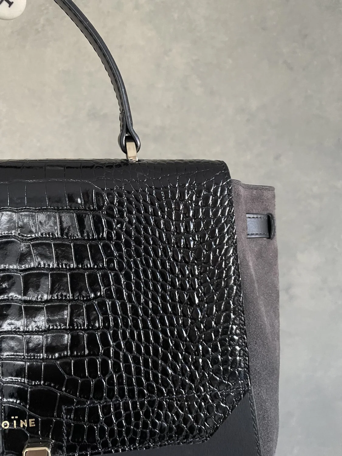 Nahaufnahme der glänzenden Krokodil-Lederprägung und des Wildleder-Seitenteils der Maison Héroïne Tasche