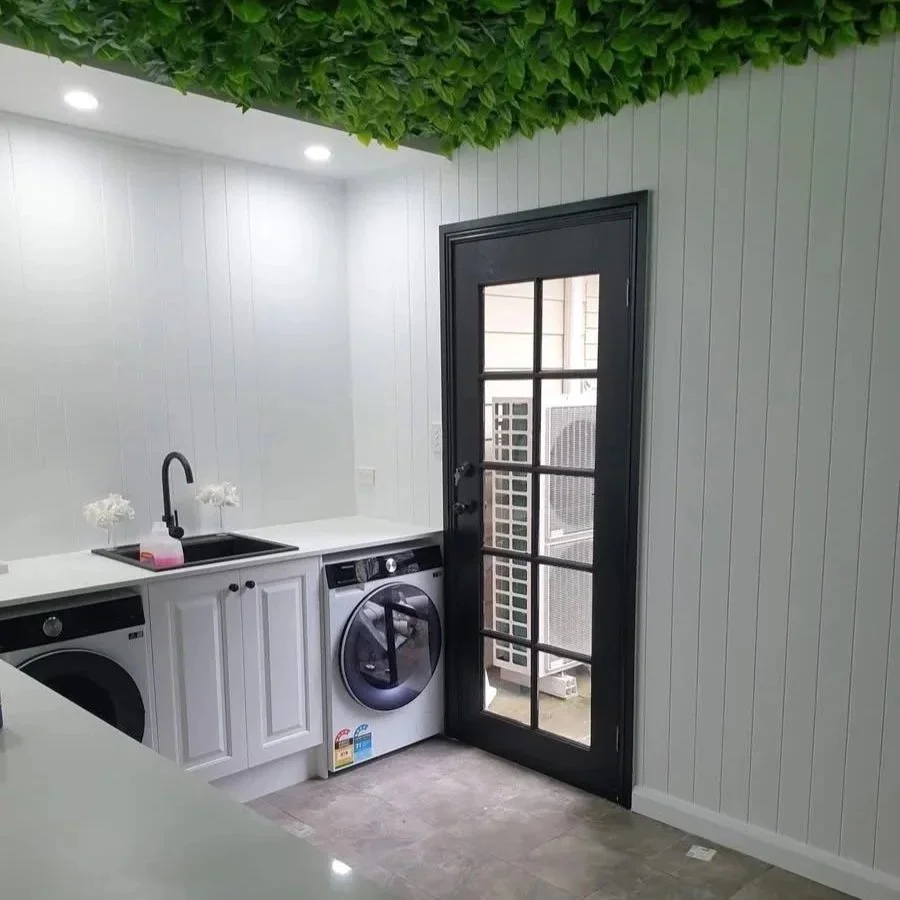 Laundry with white bench tops and cabinetry, black painted door.