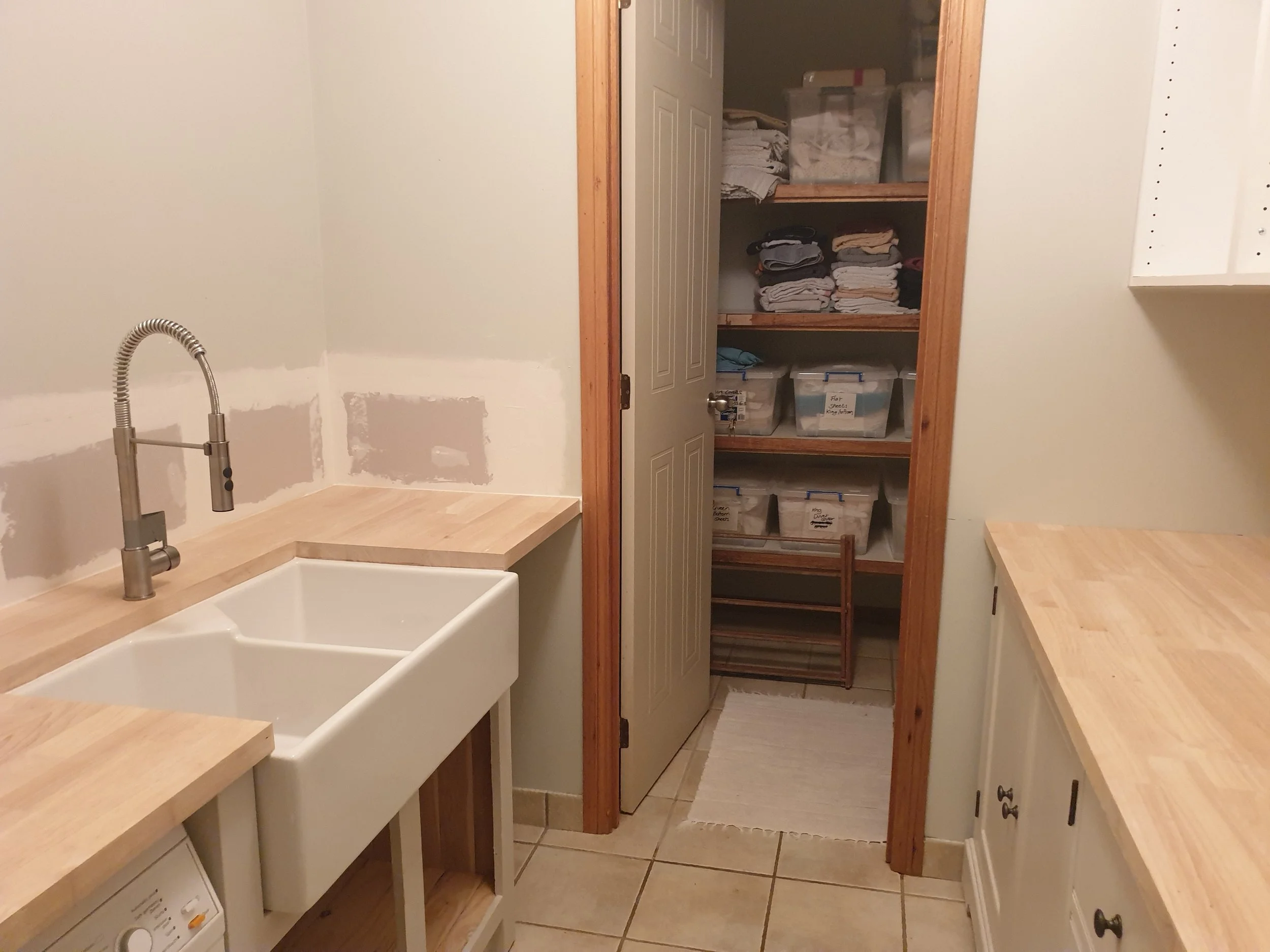 Laundry with plasterboard repairs and wooden bench tops.