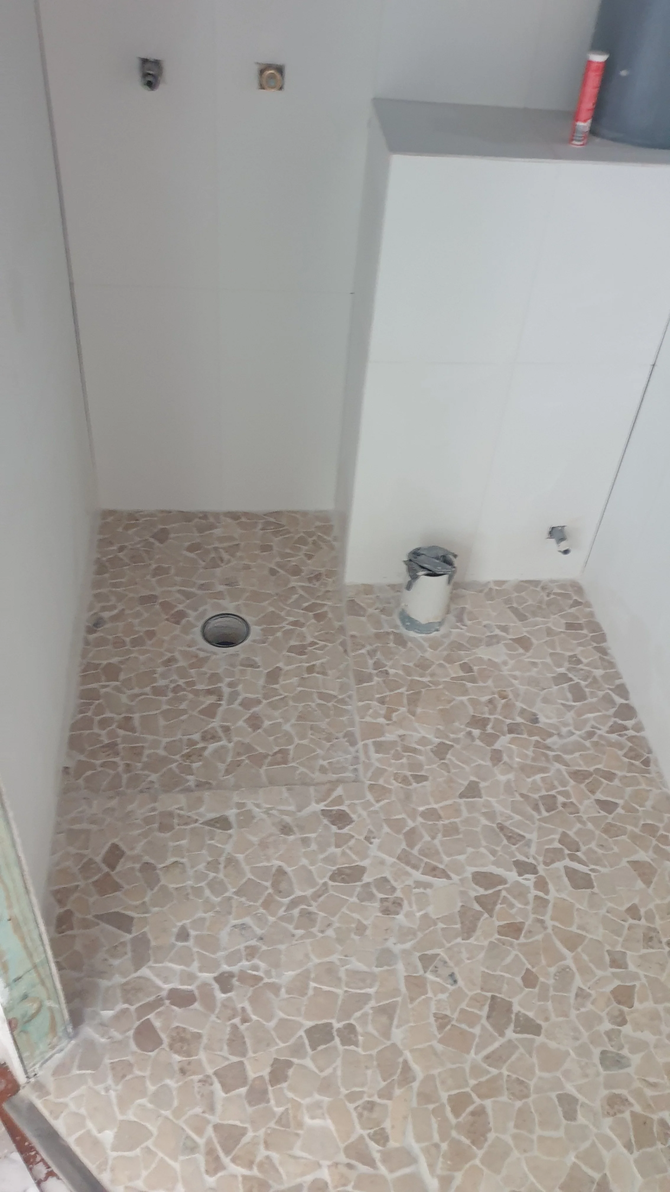small pebbled tiled floor, shower, grouting.