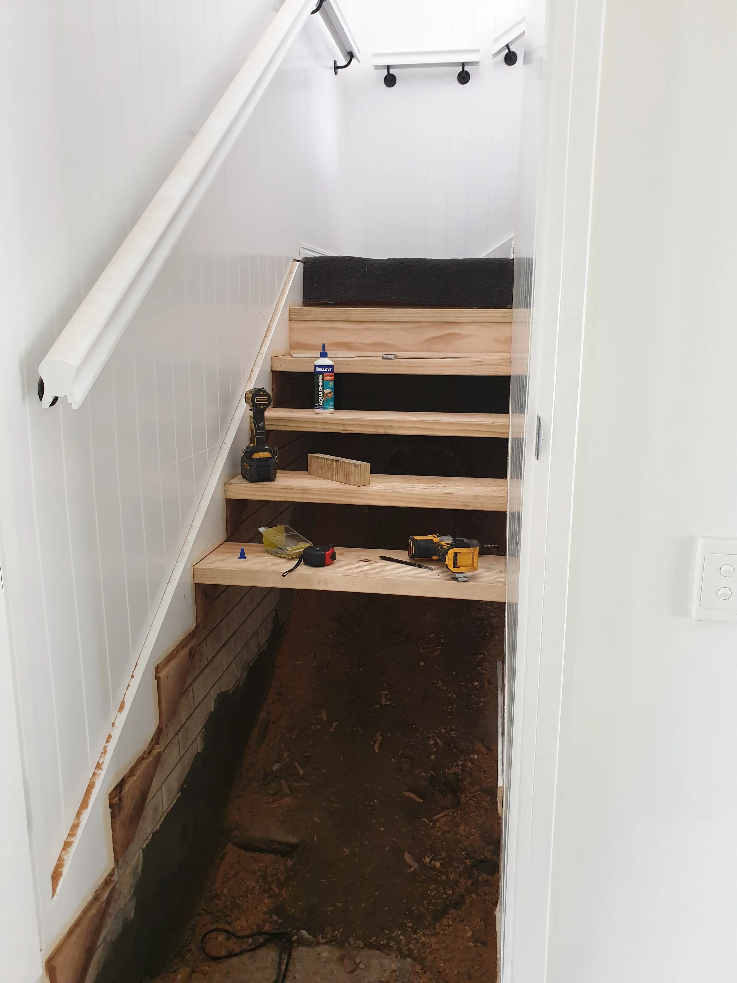 internal staircase repairs. white walls, timber stairs.