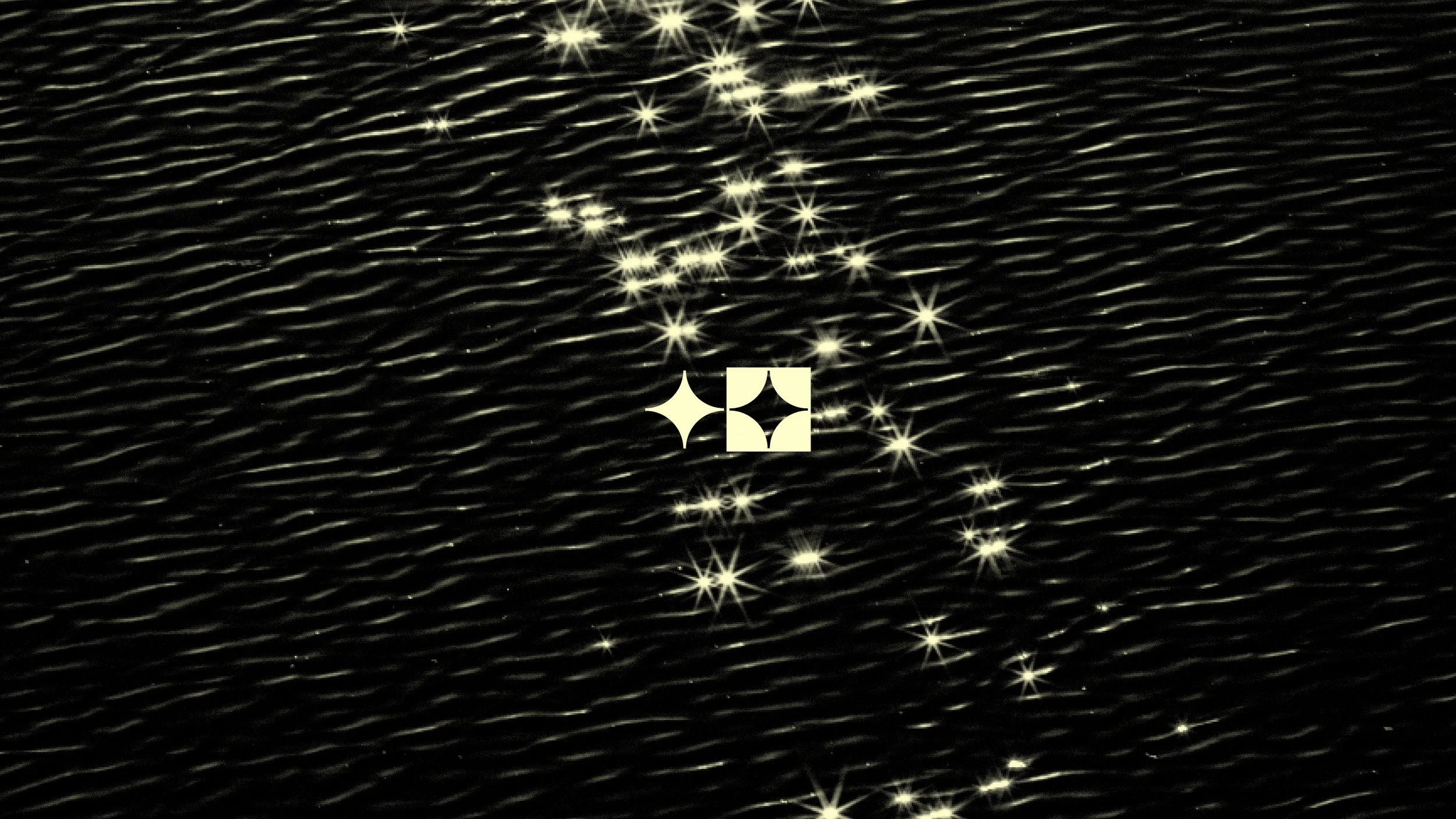 Reflections of bright lights on a dark, wavy water surface with a sparkle filter, creating star-like reflections.