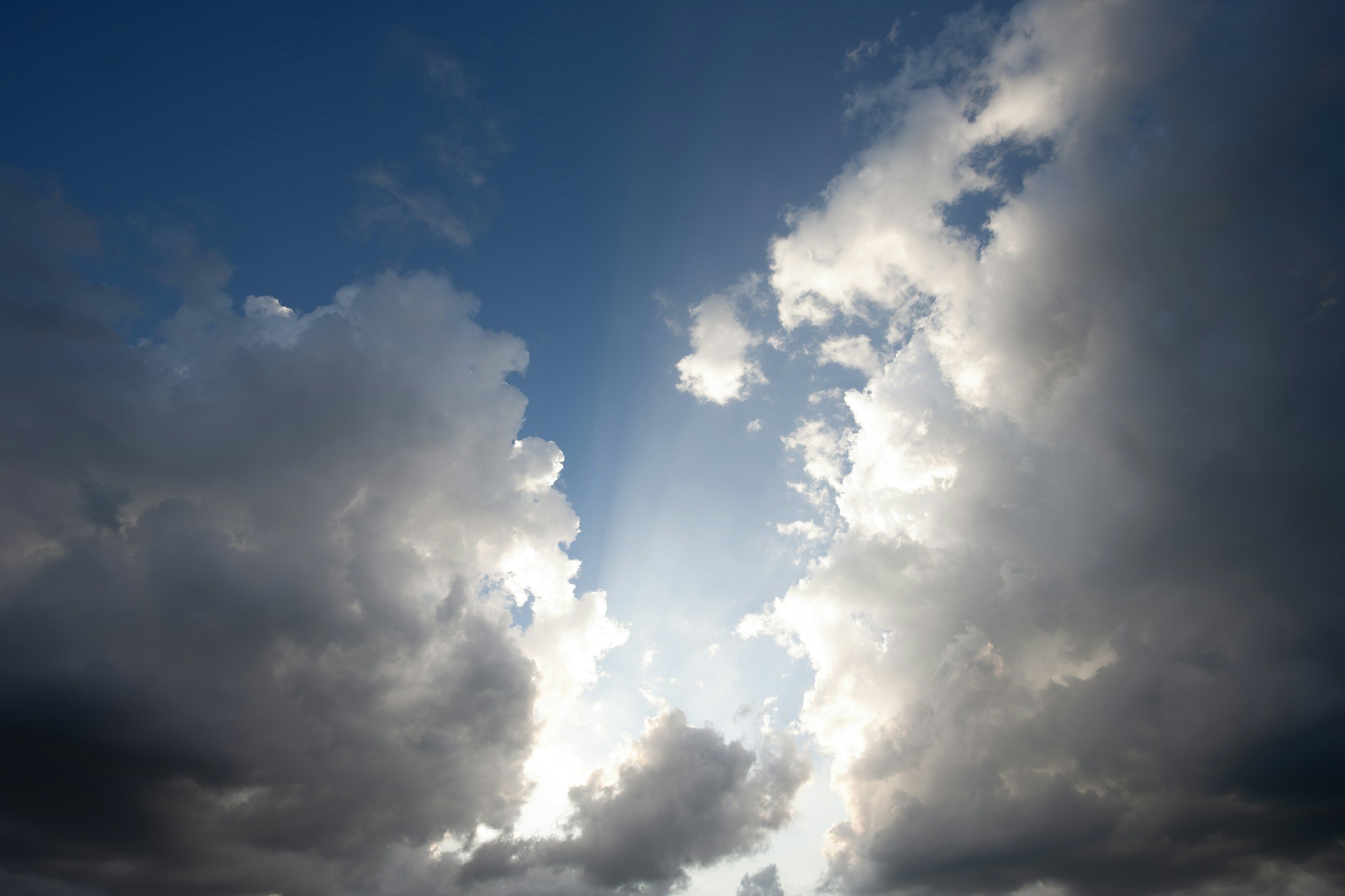 Cloudy sky with patches of blue and sunlight filtering through the clouds.