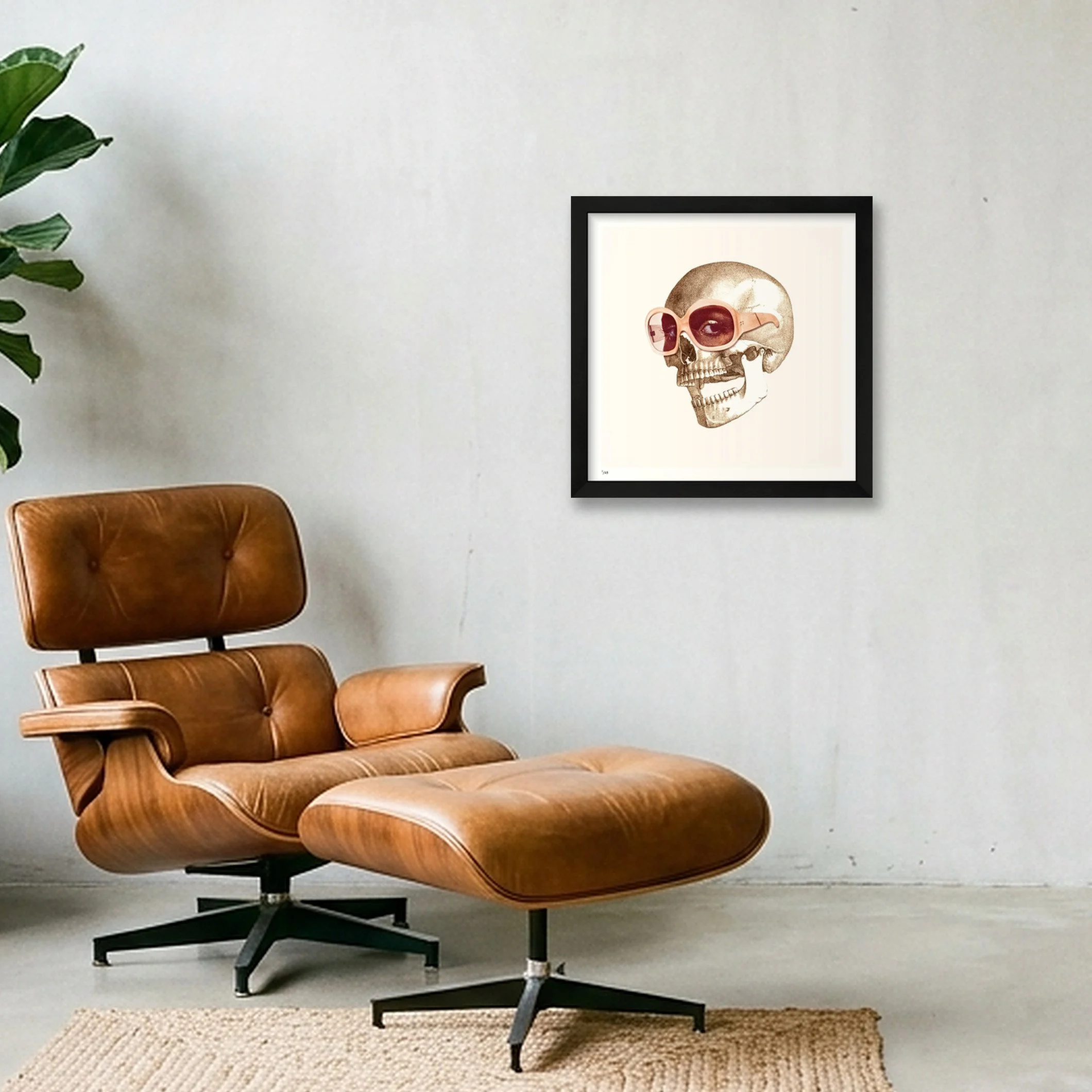 Eye Candy surreal skull art print in a black frame, displayed above a brown leather lounge chair.