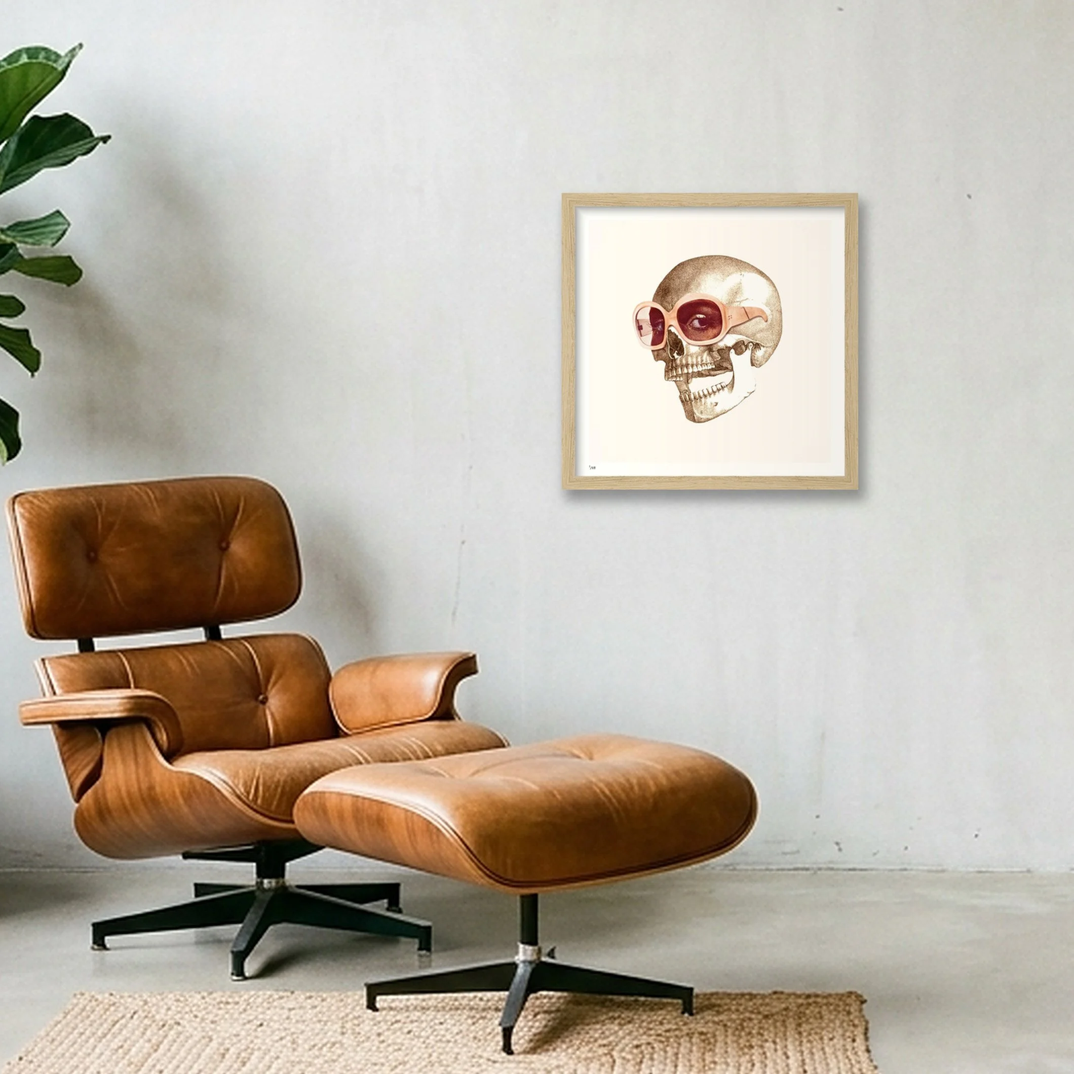 Eye Candy framed skull wall art in natural wood, displayed above a brown leather lounge chair.