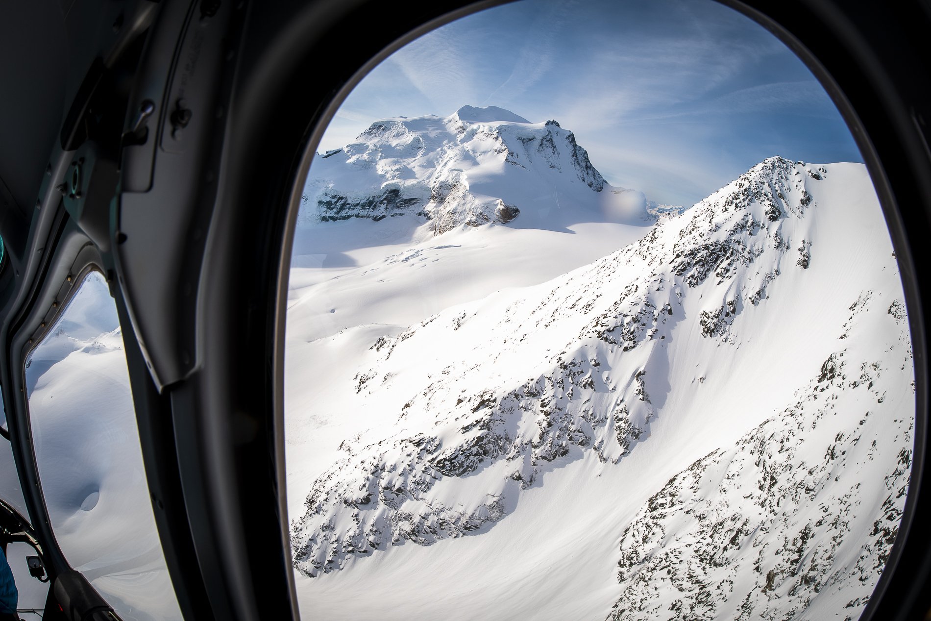 Snow-covered mountain peaks viewed through an aircraft window.