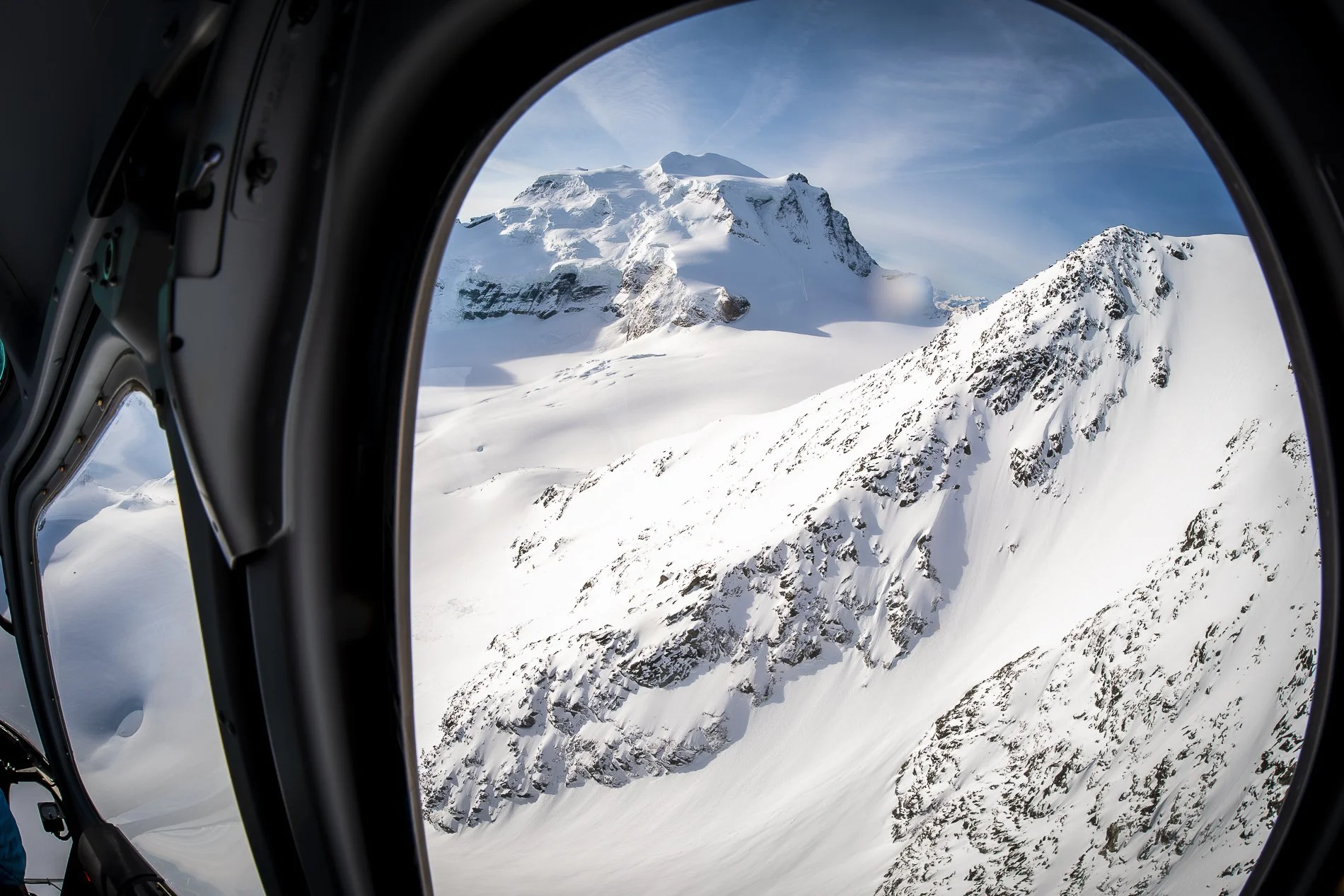 Mountain landscape with snow-covered peaks viewed through an aircraft window.
