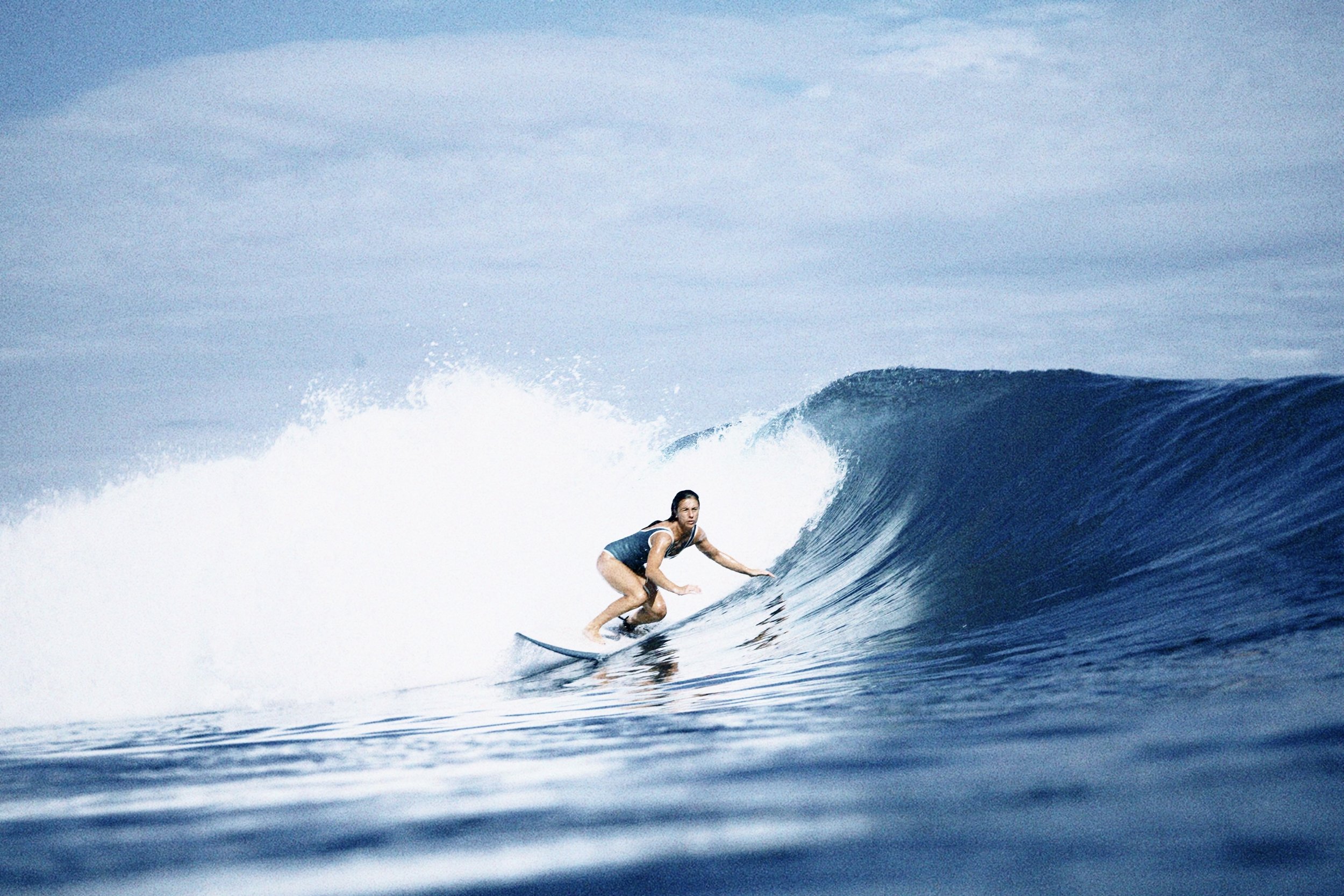 A woman surfing on a wave in the ocean during daytime.