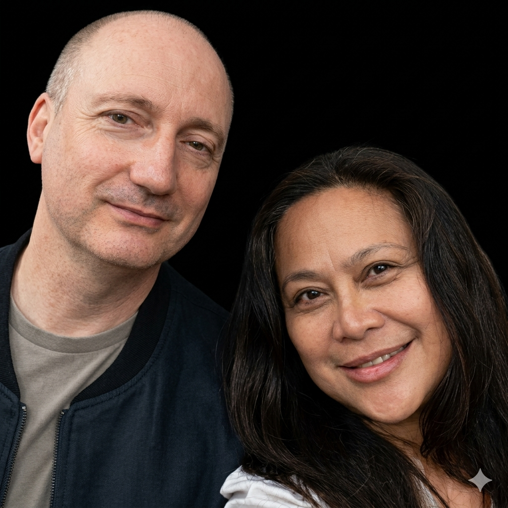 A man and a woman smiling at the camera against a black background.