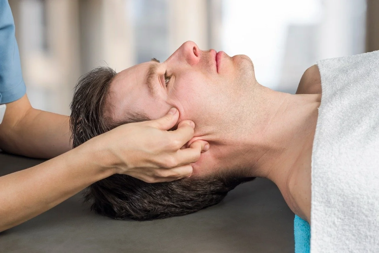 Person receiving head massage from a therapist in a spa or wellness setting.